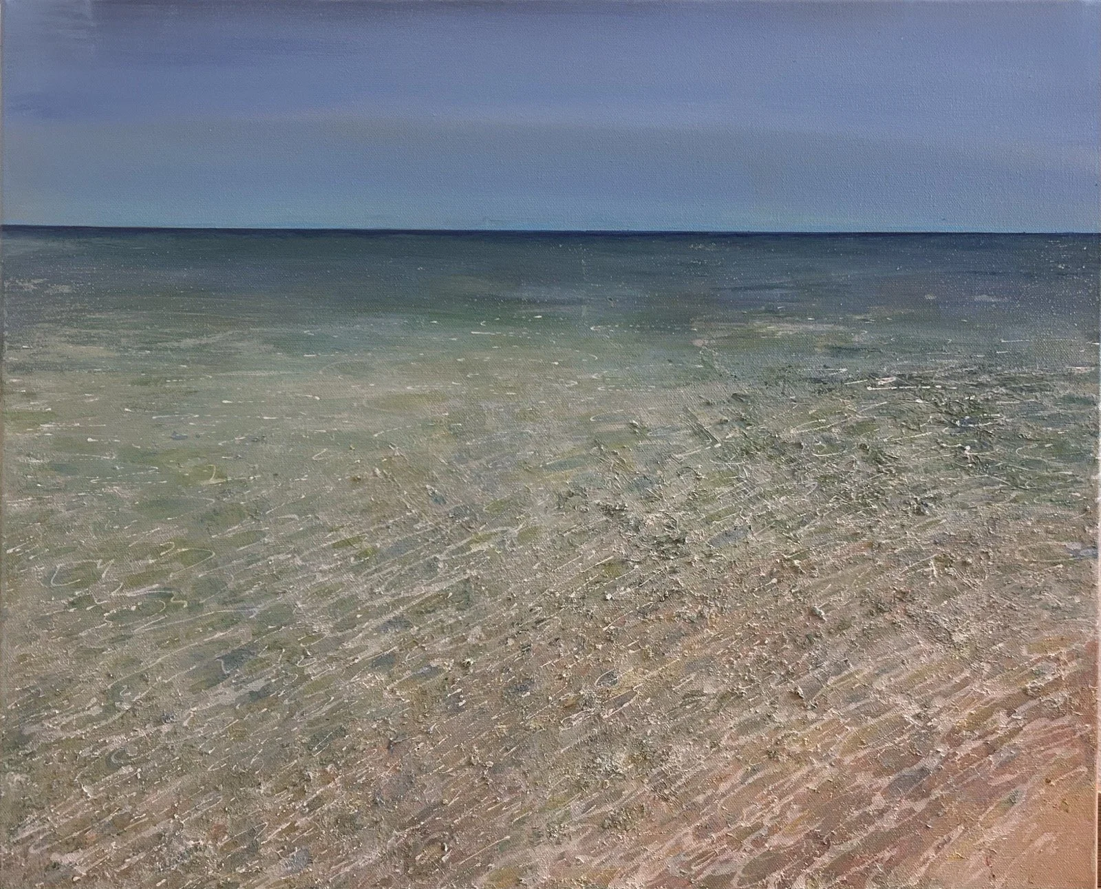 A sandy beach with gentle waves and a blue sky.