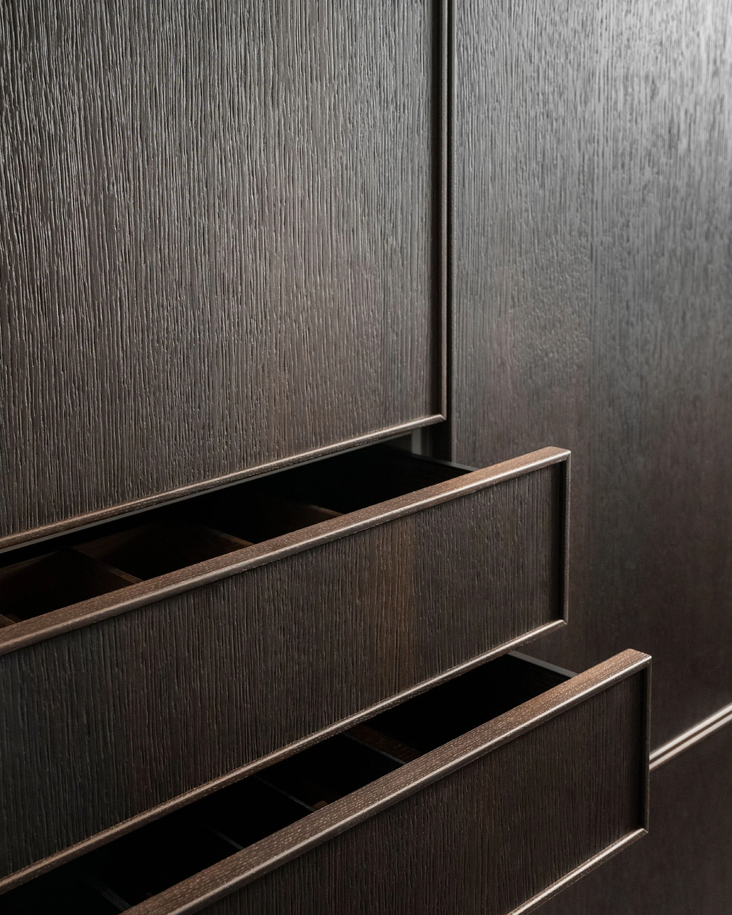 Close-up view of a textured, dark-colored elevator door with a partially opened panel at the bottom revealing a small gap.