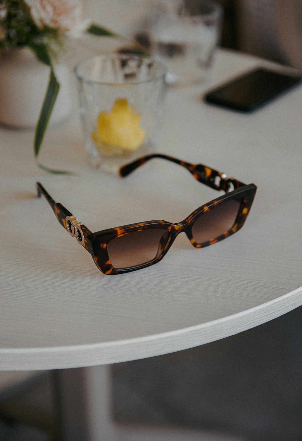 Tortoise-shell sunglasses with gradient lenses on a white round table.