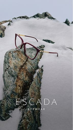 A pair of red eyeglasses resting on a rock in a snowy mountain scene with the brand name 'ESCADA EYEWEAR' at the bottom.