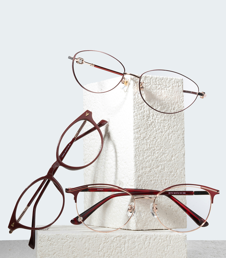 Three pairs of eyeglasses displayed on white textured blocks against a light background.