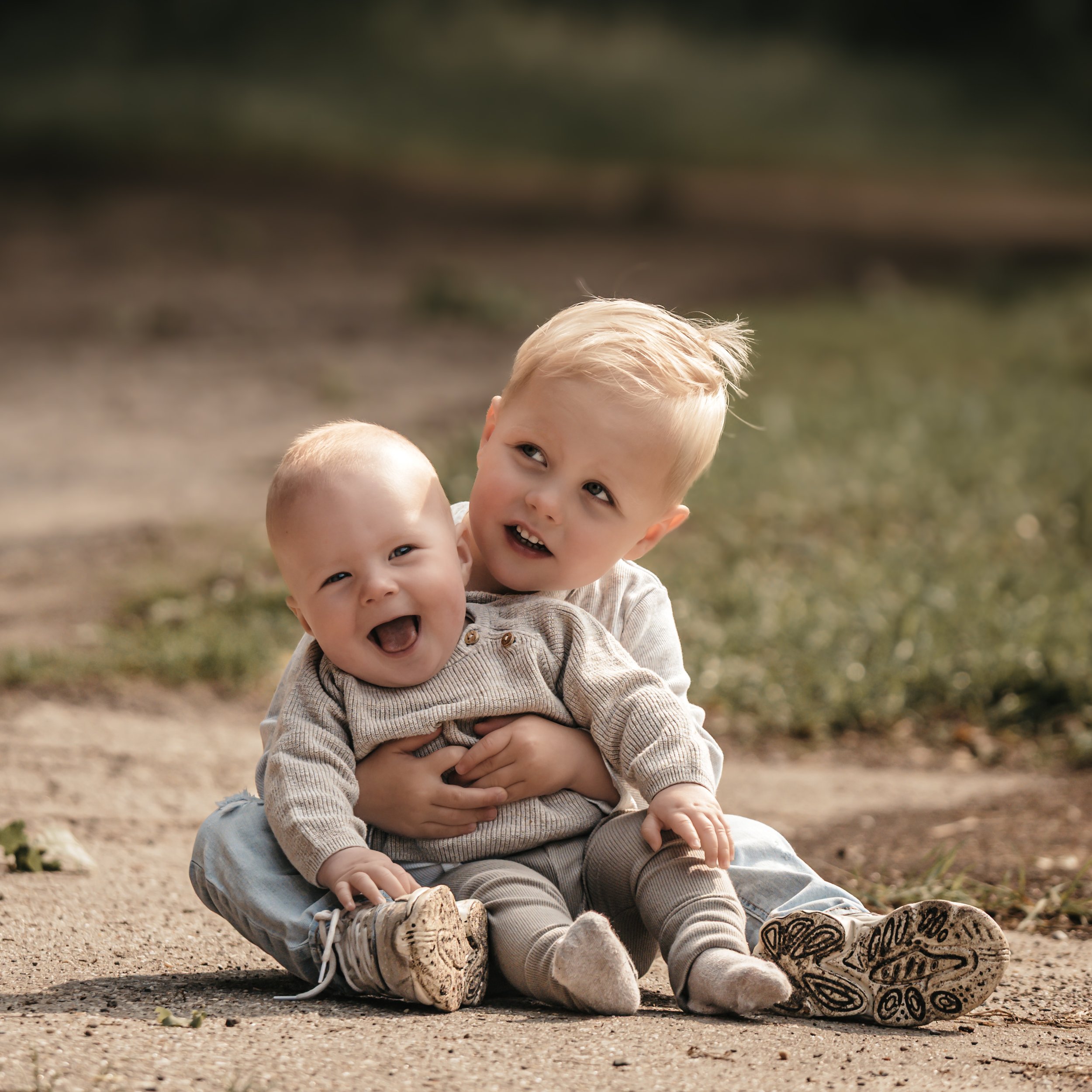 peuter met zijn lachende babybroertje tijdens gezinsshoot buiten Hengelo