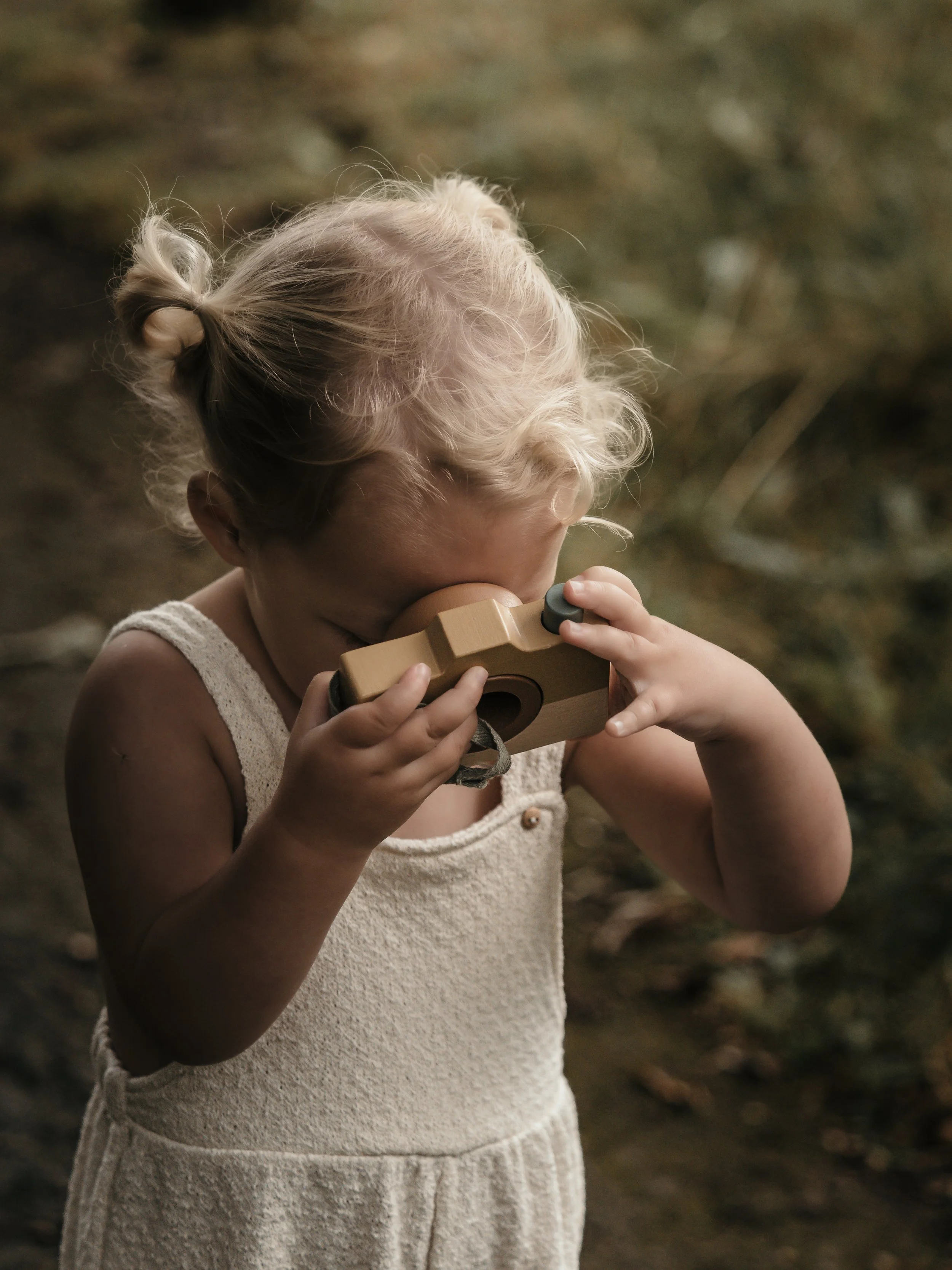 jong meisje met houten camera tijdens een newborn gezinsshoot buiten Denekamp
