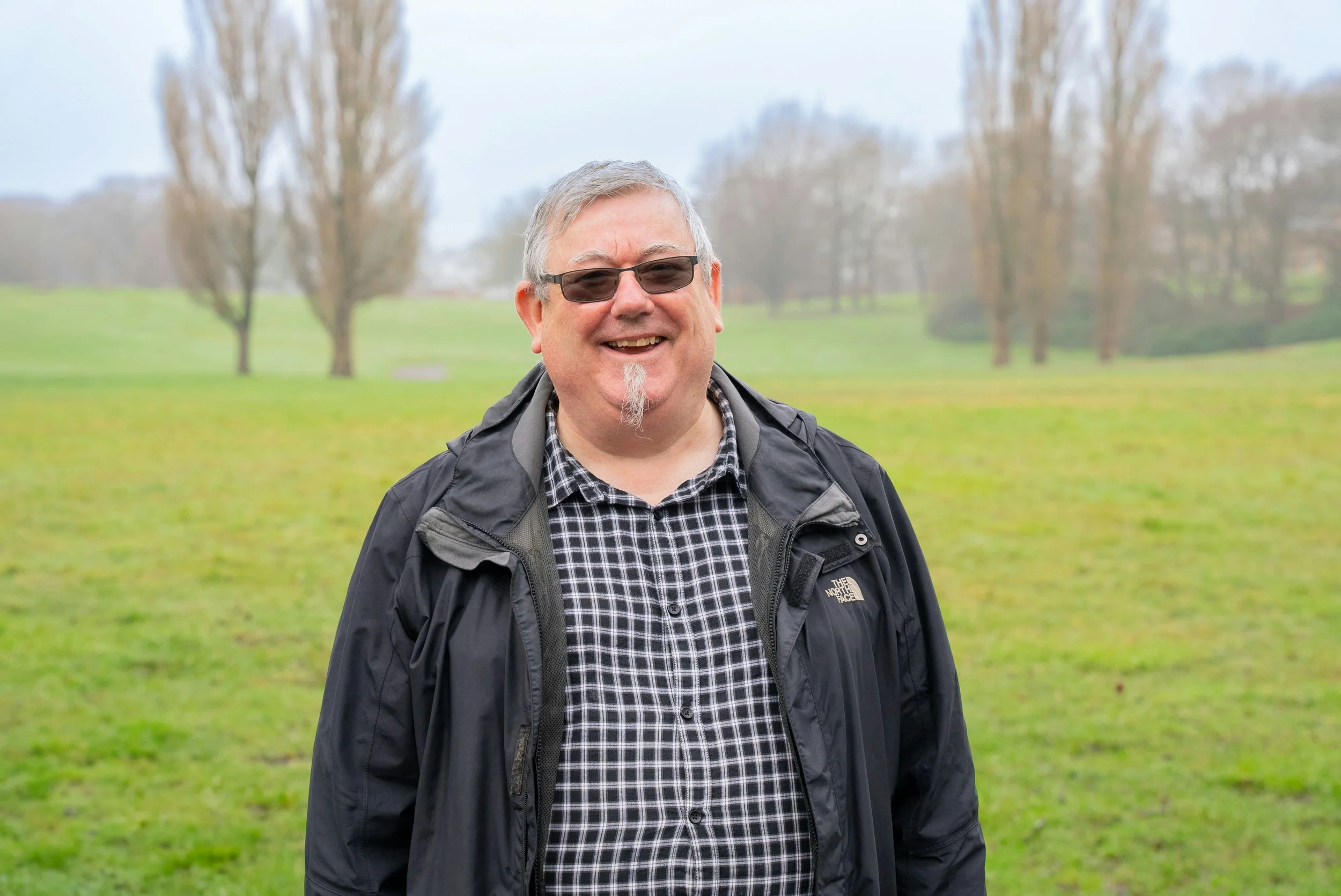 Older man smiling outdoors in a park, representing Home Grown Occupational Therapy clients in the Newcastle and Hunter region