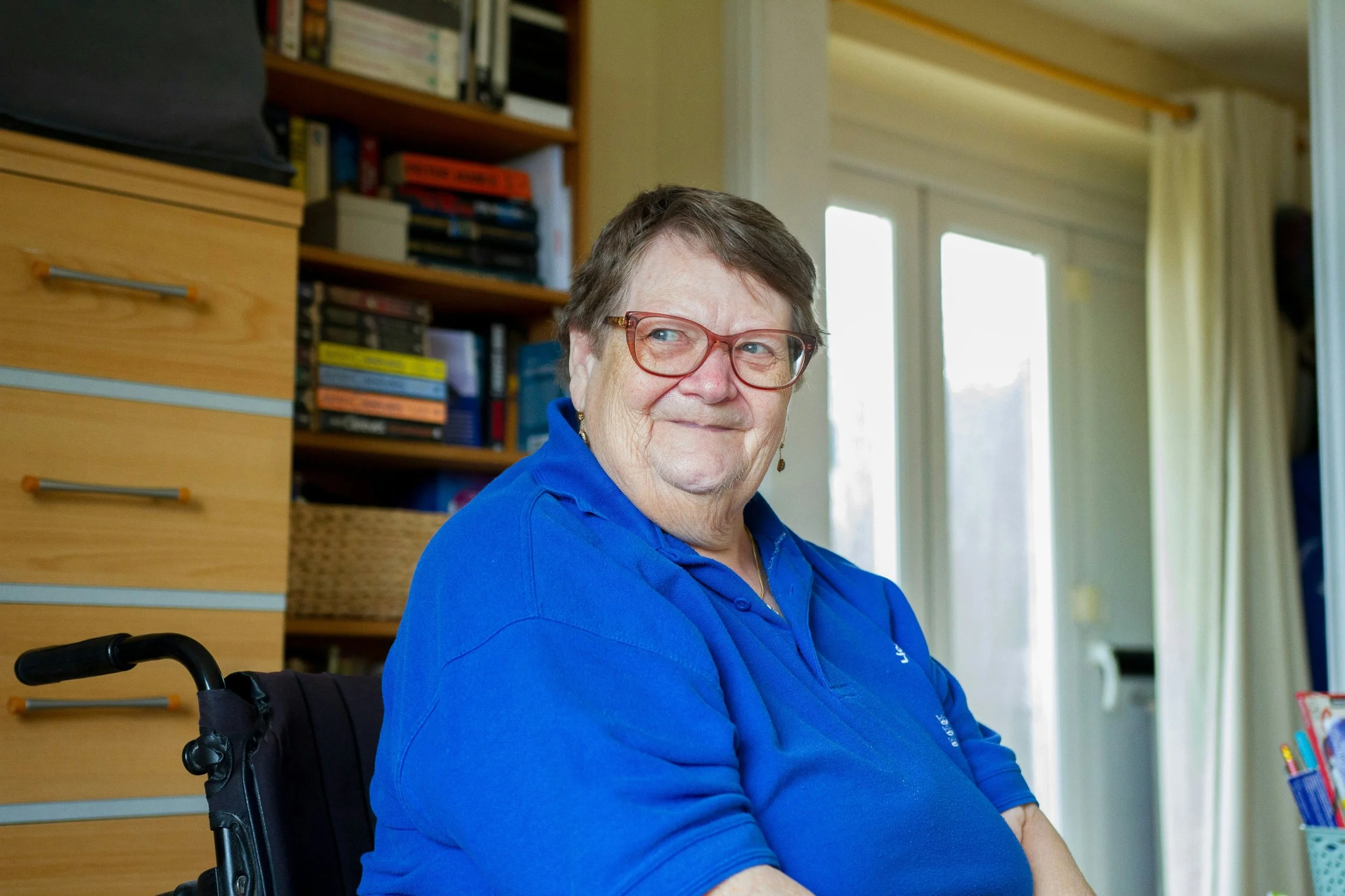 Older woman using a wheelchair smiling at home, representing NDIS occupational therapy support services in Newcastle.