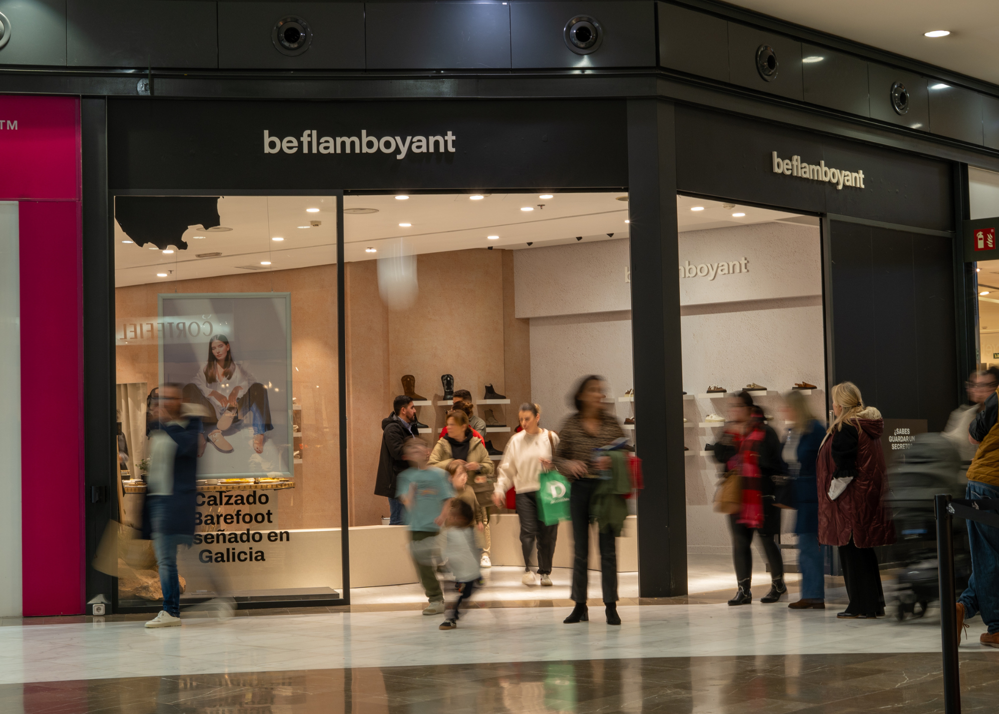 Entrada a una tienda llamada beflamboyant en un centro comercial, con varias personas caminando delante de la tienda.