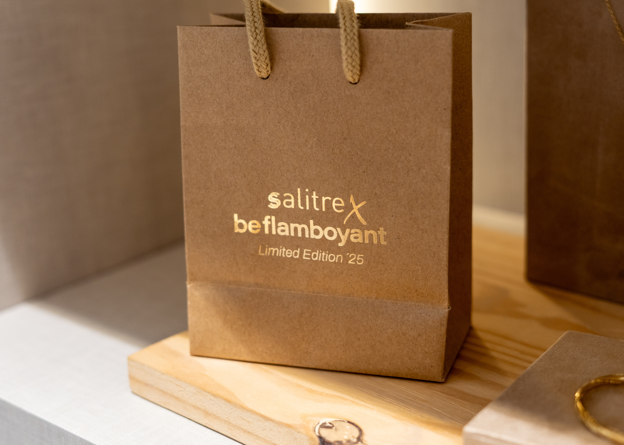 Bolsa de papel de color marrón con asas de cuerda, con texto dorado que dice 'Salitre Beflamoyant Limited Edition 25'.