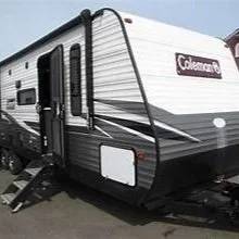 Coleman travel trailer RV with black, white, and gray exterior and side door.