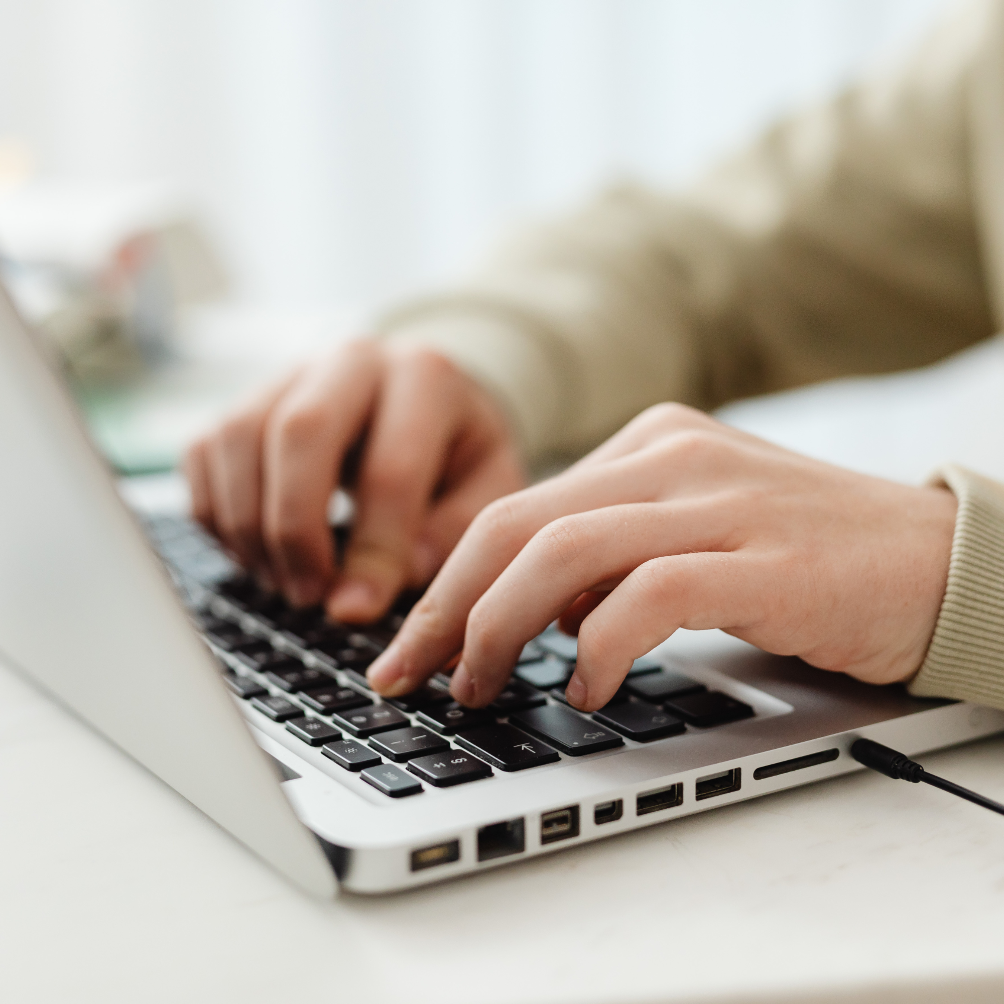 Close-up of hands typing on a laptop keyboard.