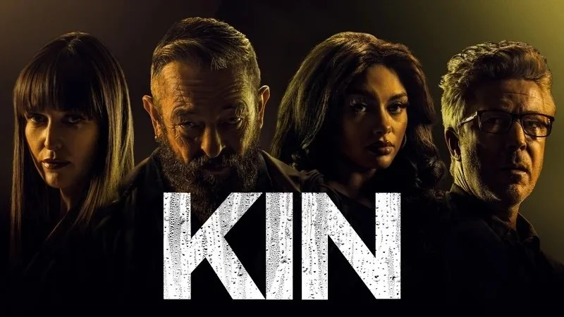 Group photo of four people with dark lighting, the word "KIN" in large distressed white letters at the bottom.
