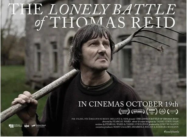 Poster for the film "The Lonely Battle of Thomas Reid" showing a man with dark hair holding a large stick over his shoulder, standing outdoors near an old stone building, with text indicating a September 19th cinema release.