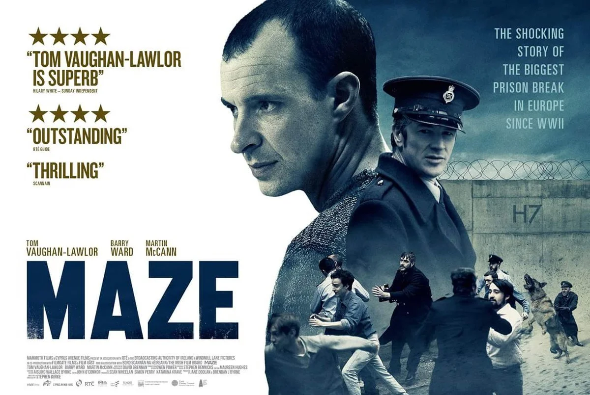 Movie poster for 'Maze' featuring a large face of Tom Vaughan-Lawlor on the right, a police officer, a prison wall with a barbed wire fence, and several people running or fighting in front of the wall.