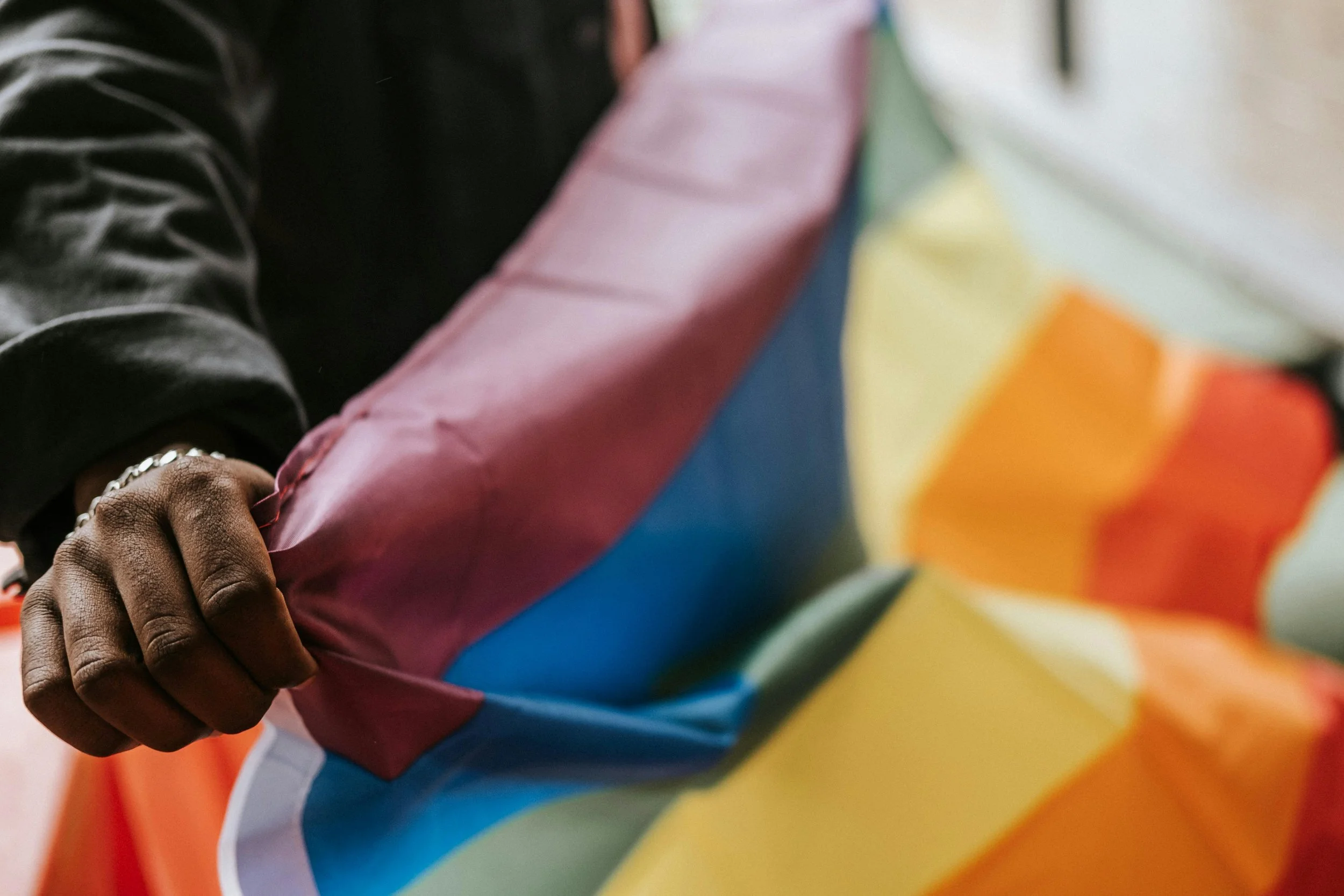 A person holding a progress pride flag as they march outside.