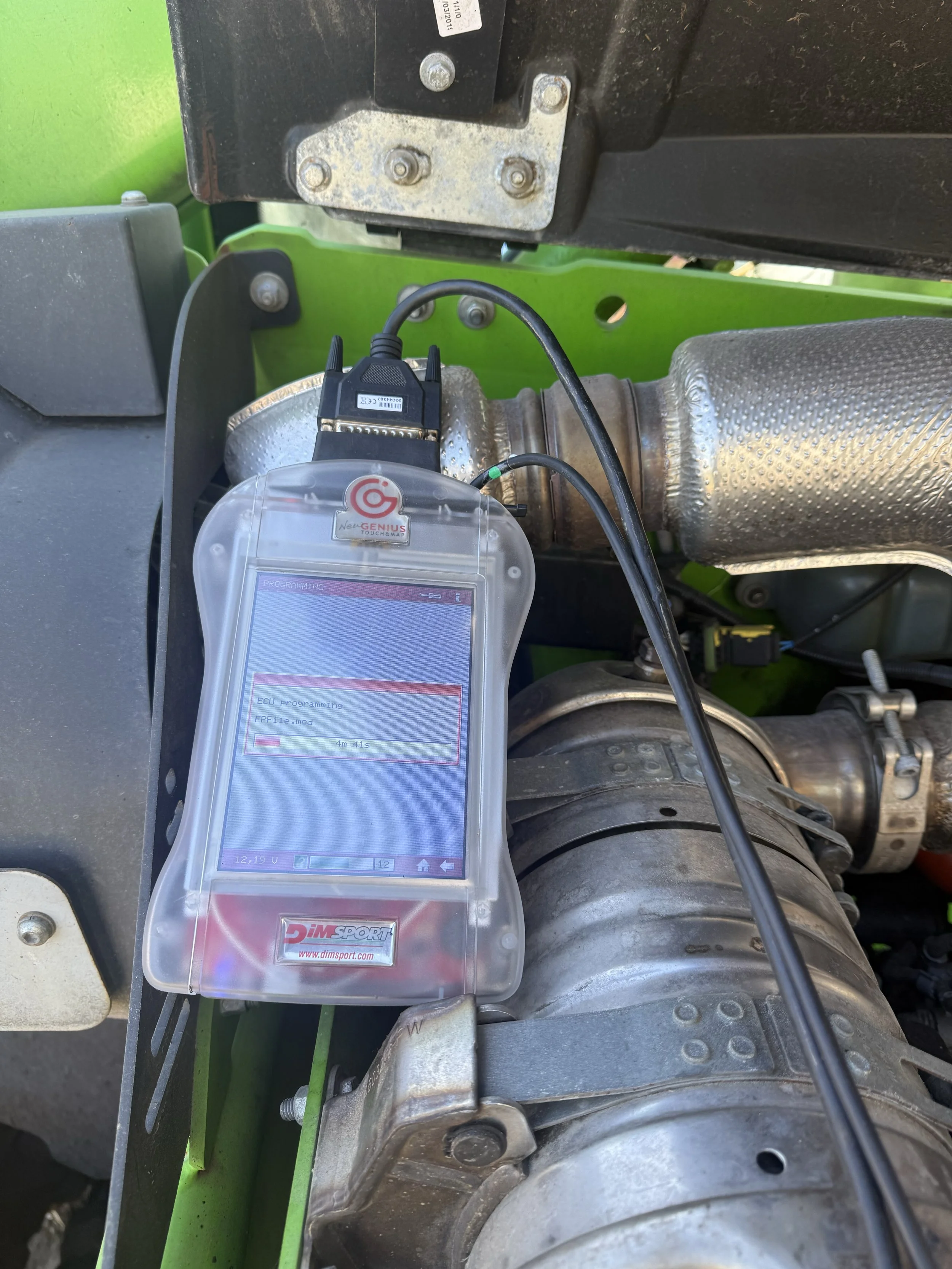 Close-up view of diagnostic equipment connected to a vehicle's engine with green and metallic components visible.