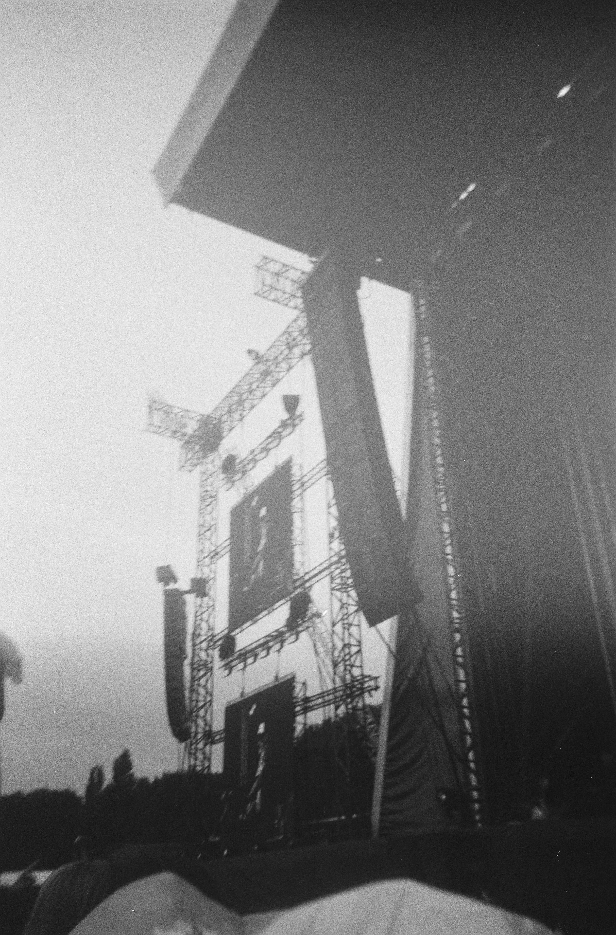 A black and white photograph of an electricity pylon holding power lines with a clear sky in the background.