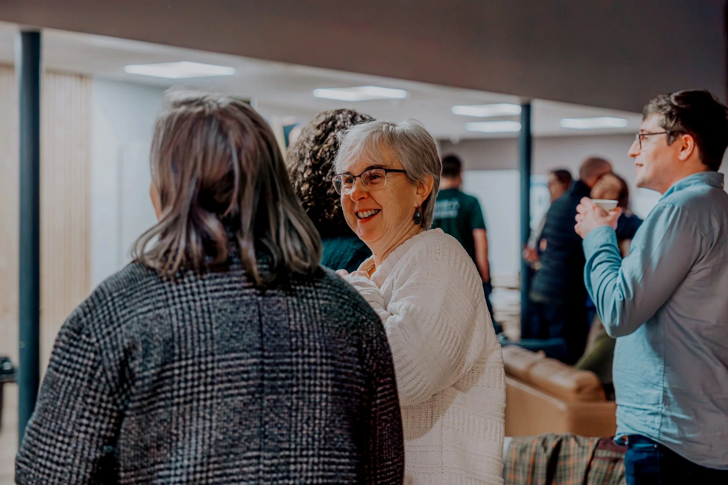 People talking and socializing at an indoor gathering or event.