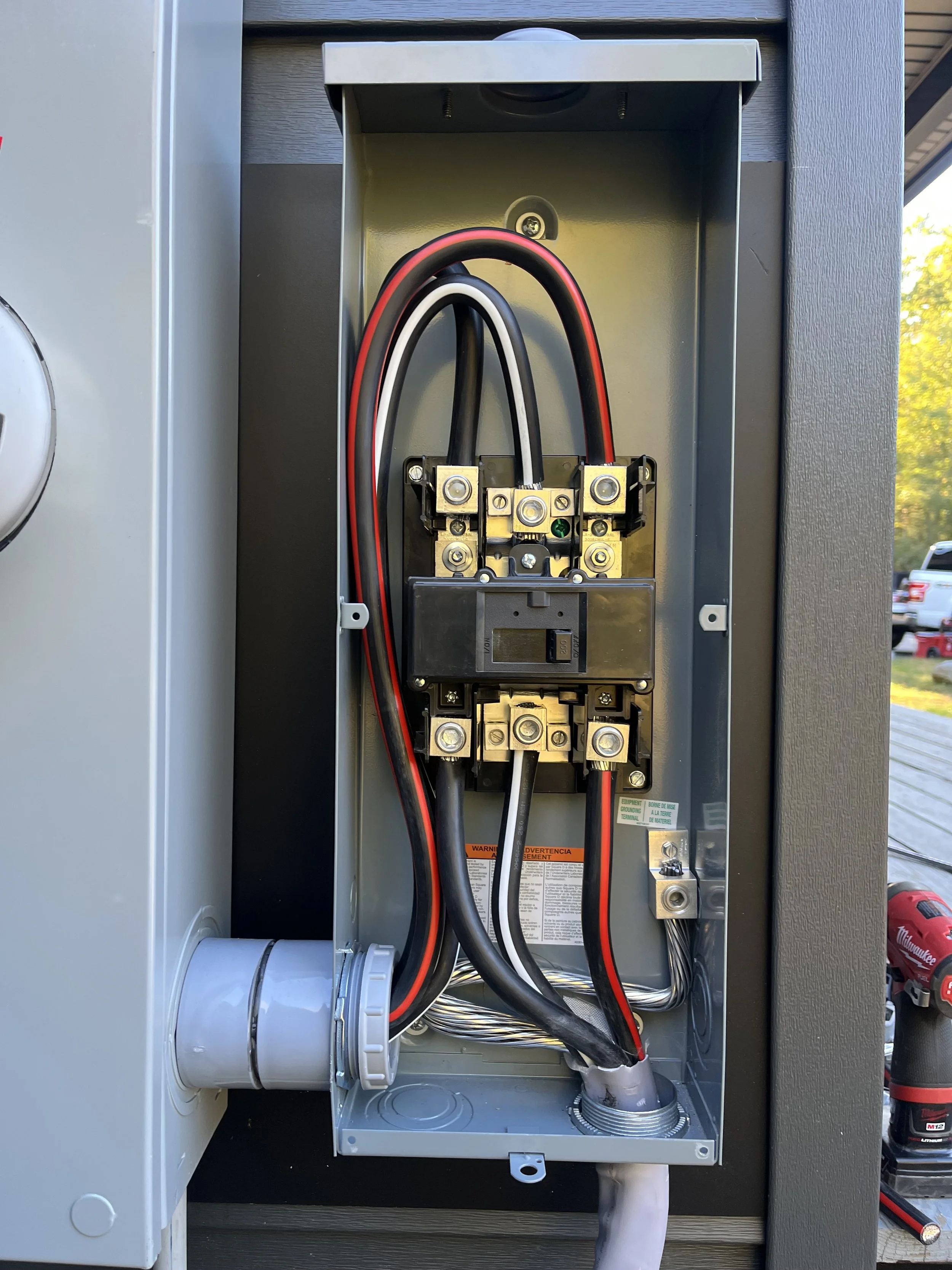 An open electrical utility box with wiring and circuit breakers visible inside.