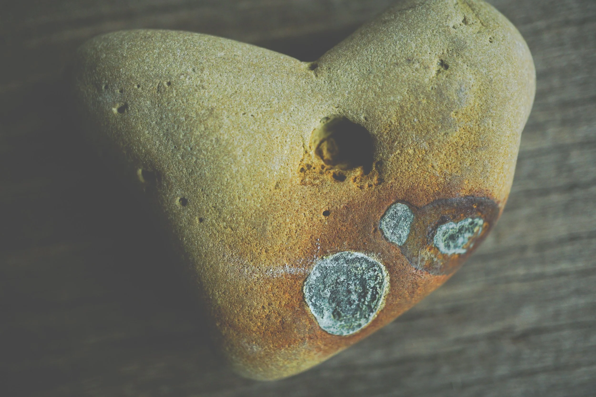 Close-up of a heart-shaped stone on a wooden surface.