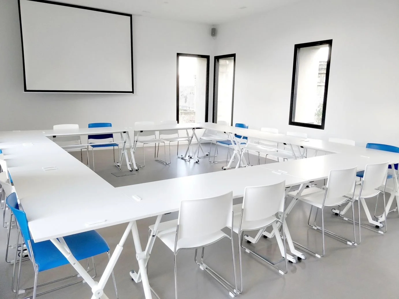 Salle de réunion modulable en configuration carré avec tables et écran de projection, location de salle à Nantes chez Rokyo à Trentemoult