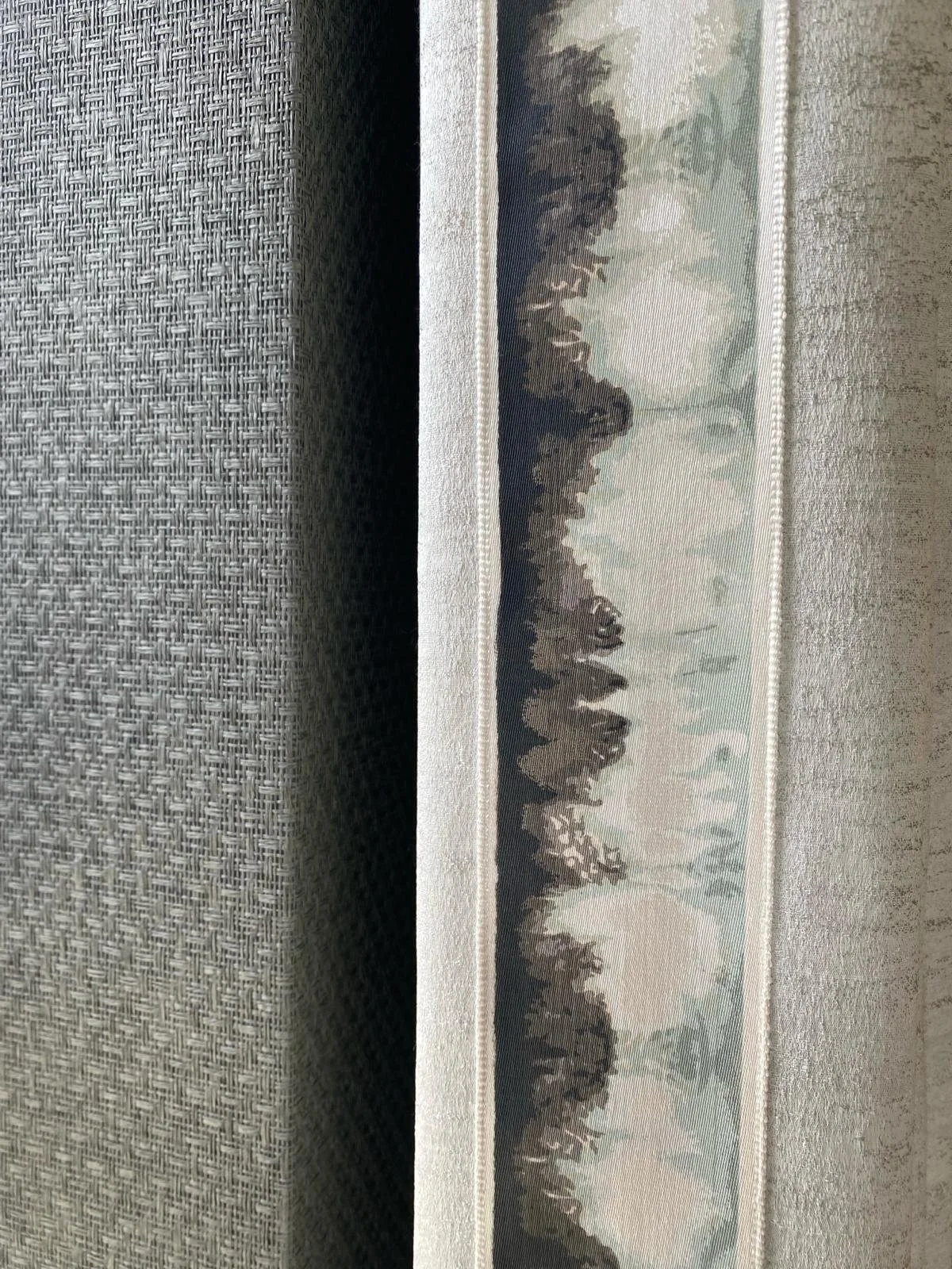 A close up detail of a curtain trim with against a textured wallpaper. 