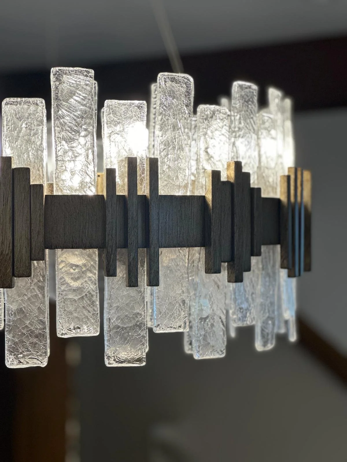 Close-up of a modern chandelier with textured glass rectangular pieces and wooden accents.