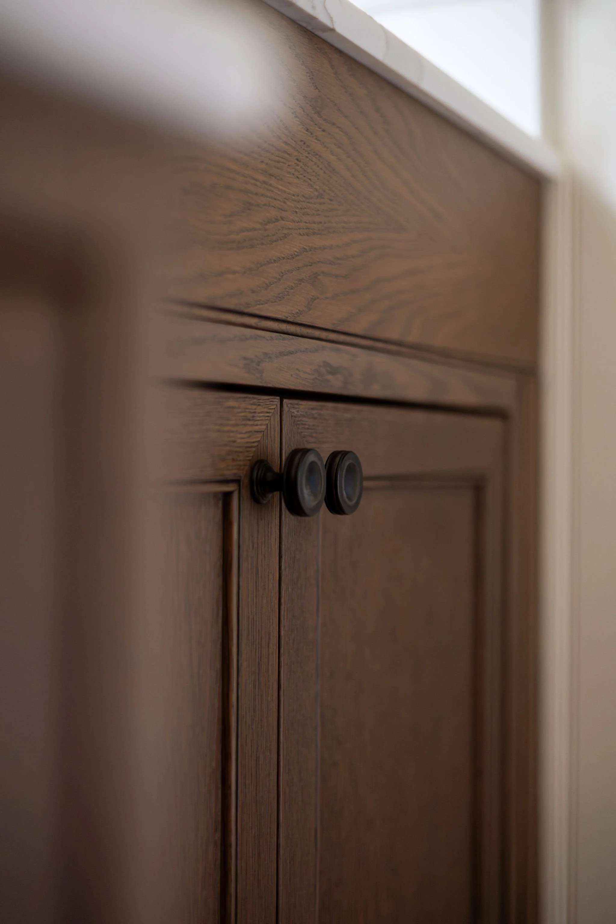 Close-up of a wooden cabinet with black round knobs, showing the wood grain pattern.