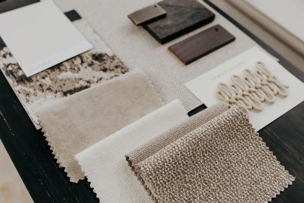 Various fabric and material samples, including swatches of upholstery, wood, and textile samples on a table.