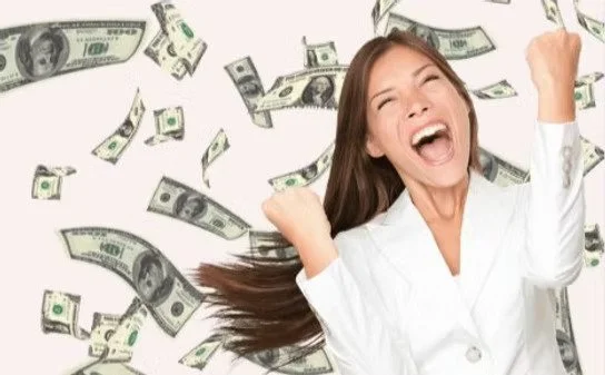 A woman celebrating with dollar bills falling around her.