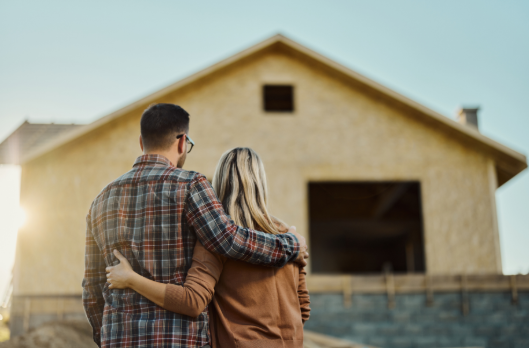 A couple embracing while looking at a house under construction.