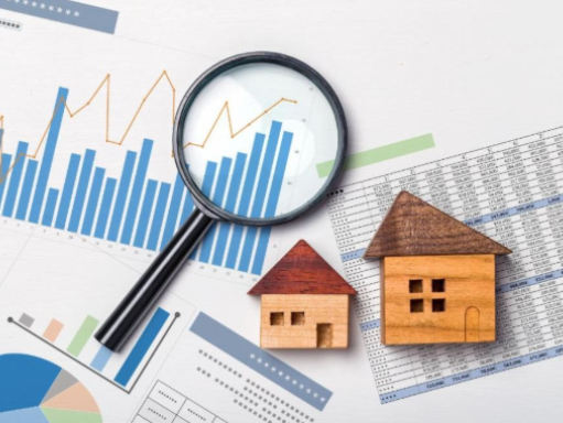 Two small wooden house models placed on financial reports under a magnifying glass, with graphs and data charts in the background.