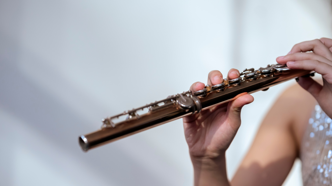 Person playing the flute, close-up of hands holding the instrument.