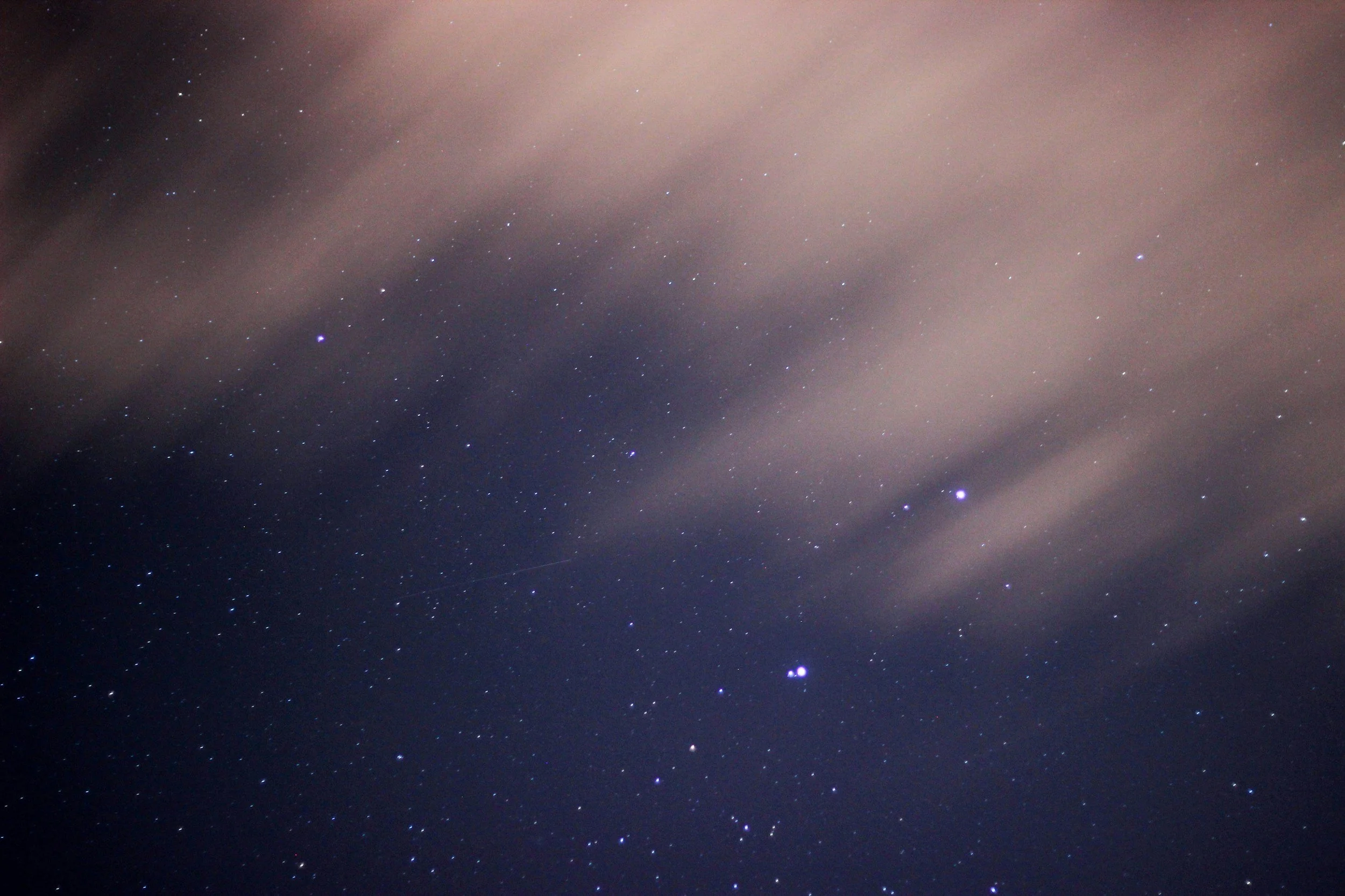 Night sky with numerous stars and a few clouds.