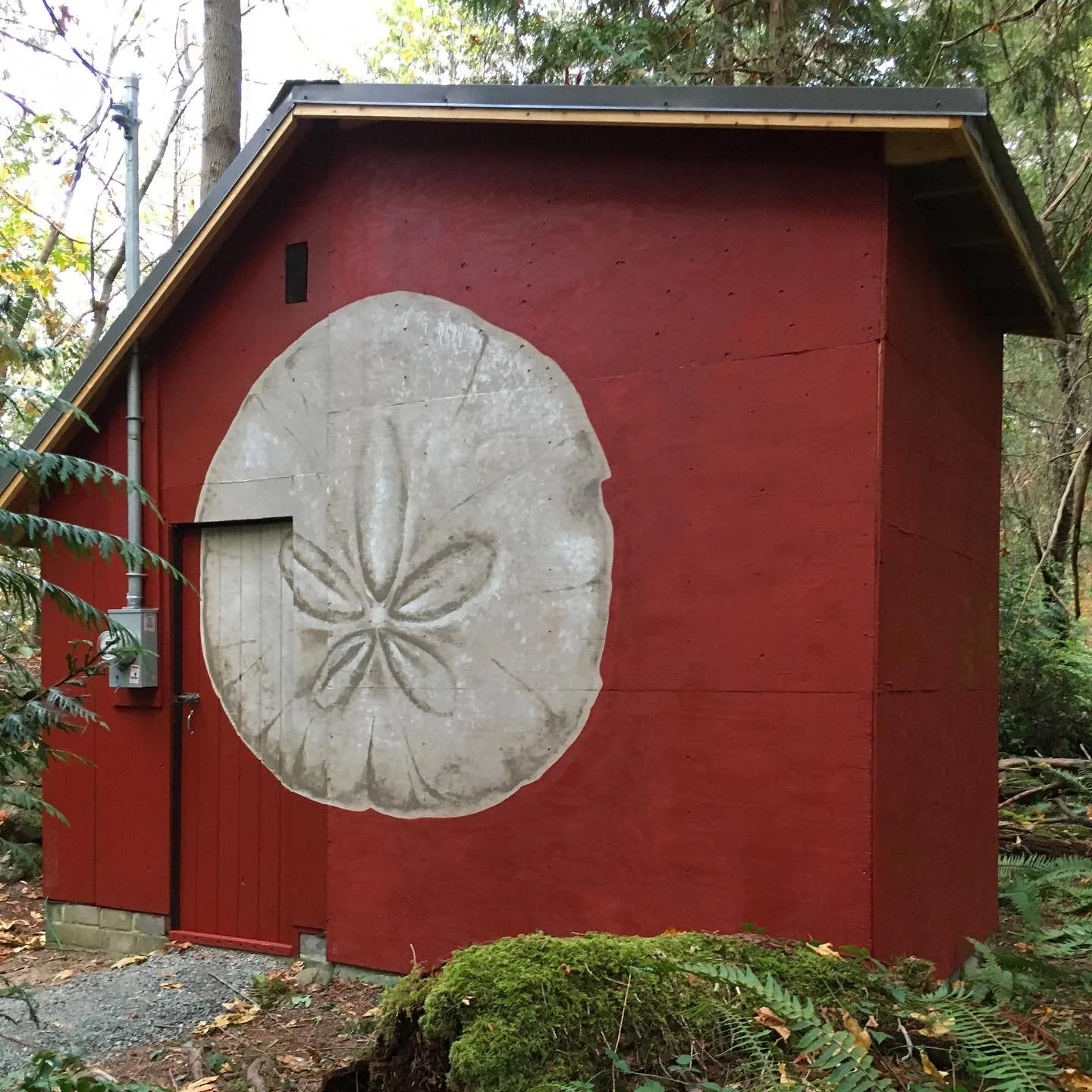 Mur rouge avec une peinture d'une tranche de citron sur le côté d'une maison en forêt.