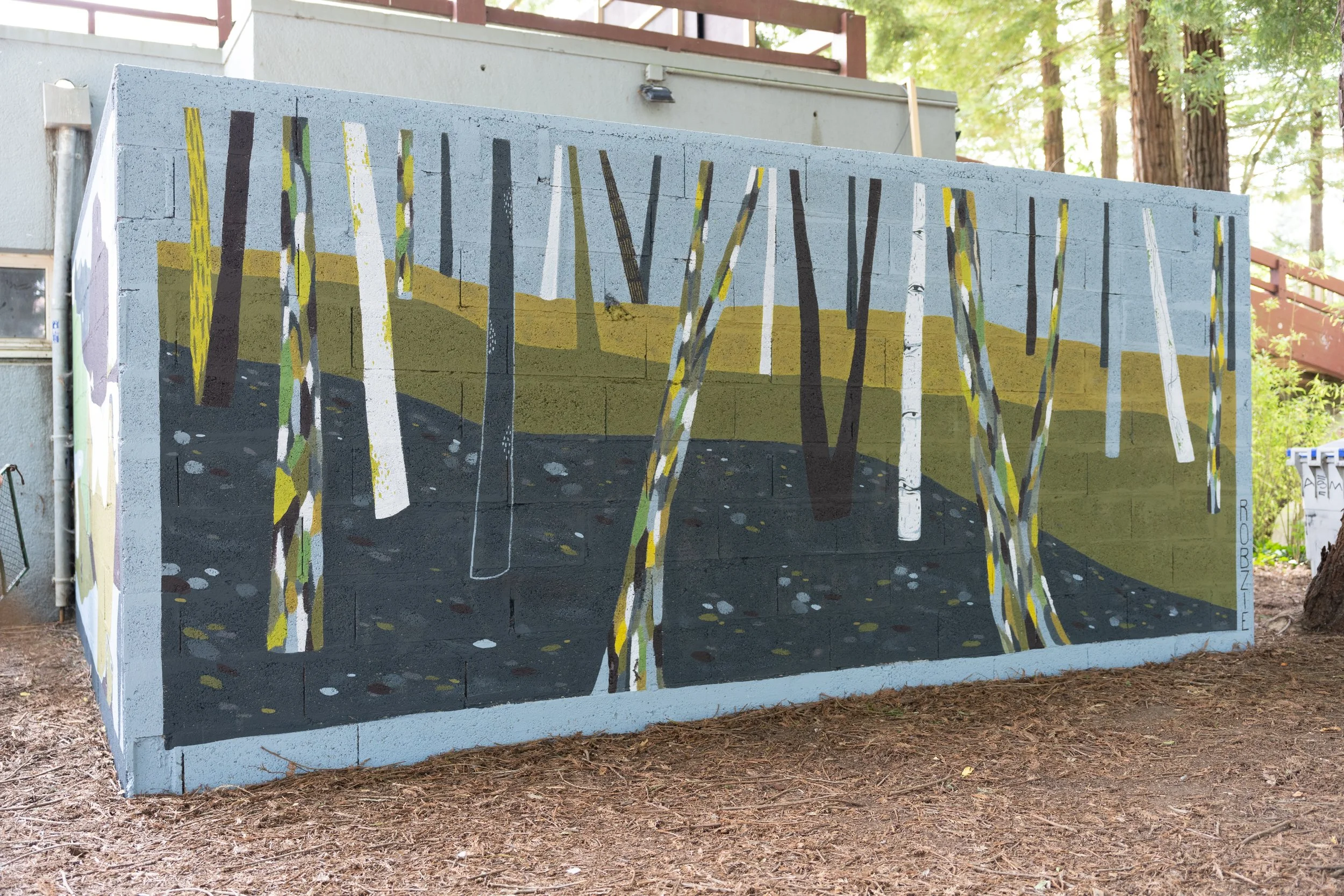 Mur peint représentant une forêt avec des arbres, dans un style artistique abstrait, situé à l'extérieur sur un mur en béton près d'arbres et de bâtiments.
