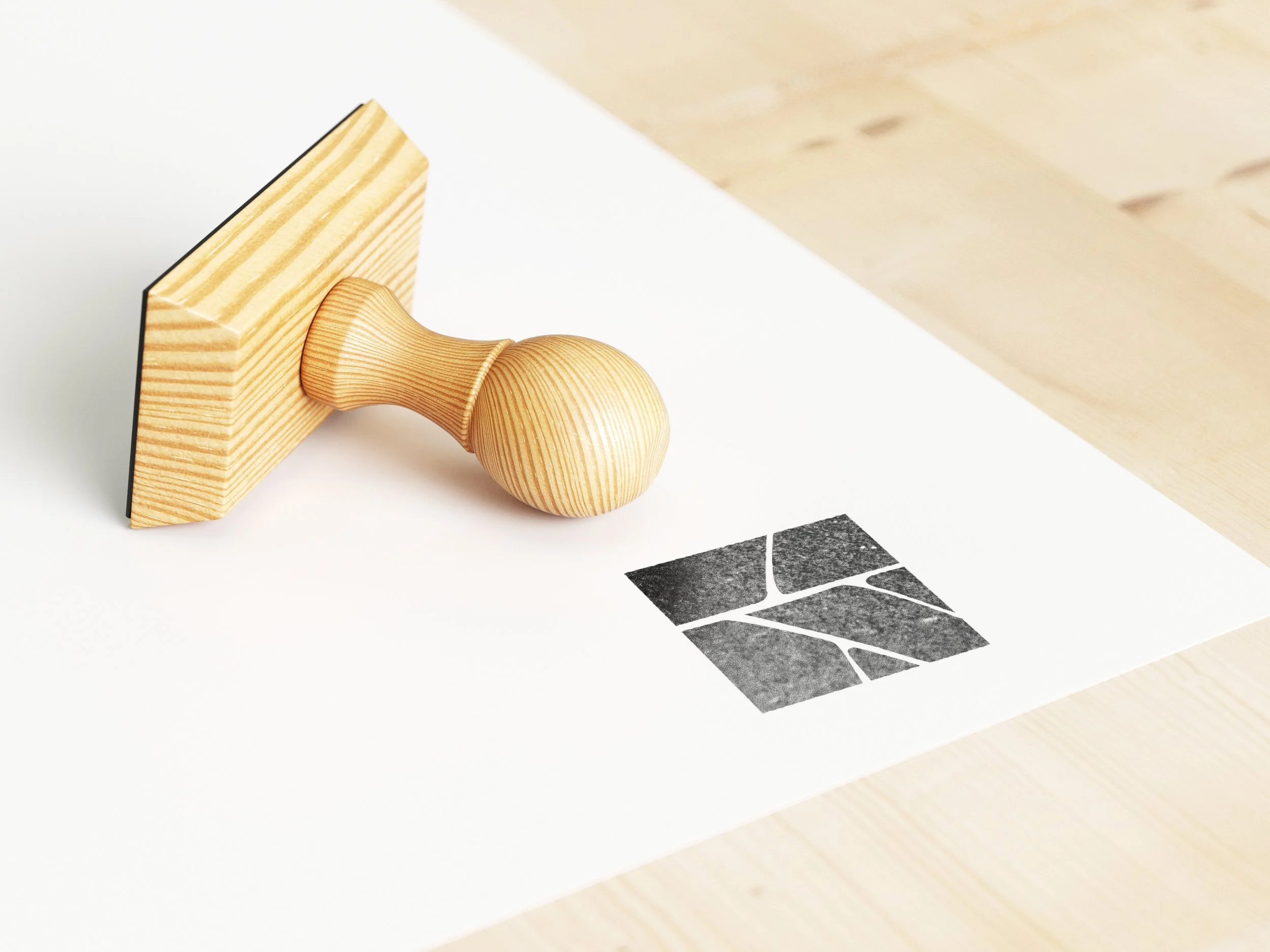 Un tampon en bois posé sur une surface blanche, avec une image en noir et blanc d'un arbre ou d'une plante en partie visible en dessous.