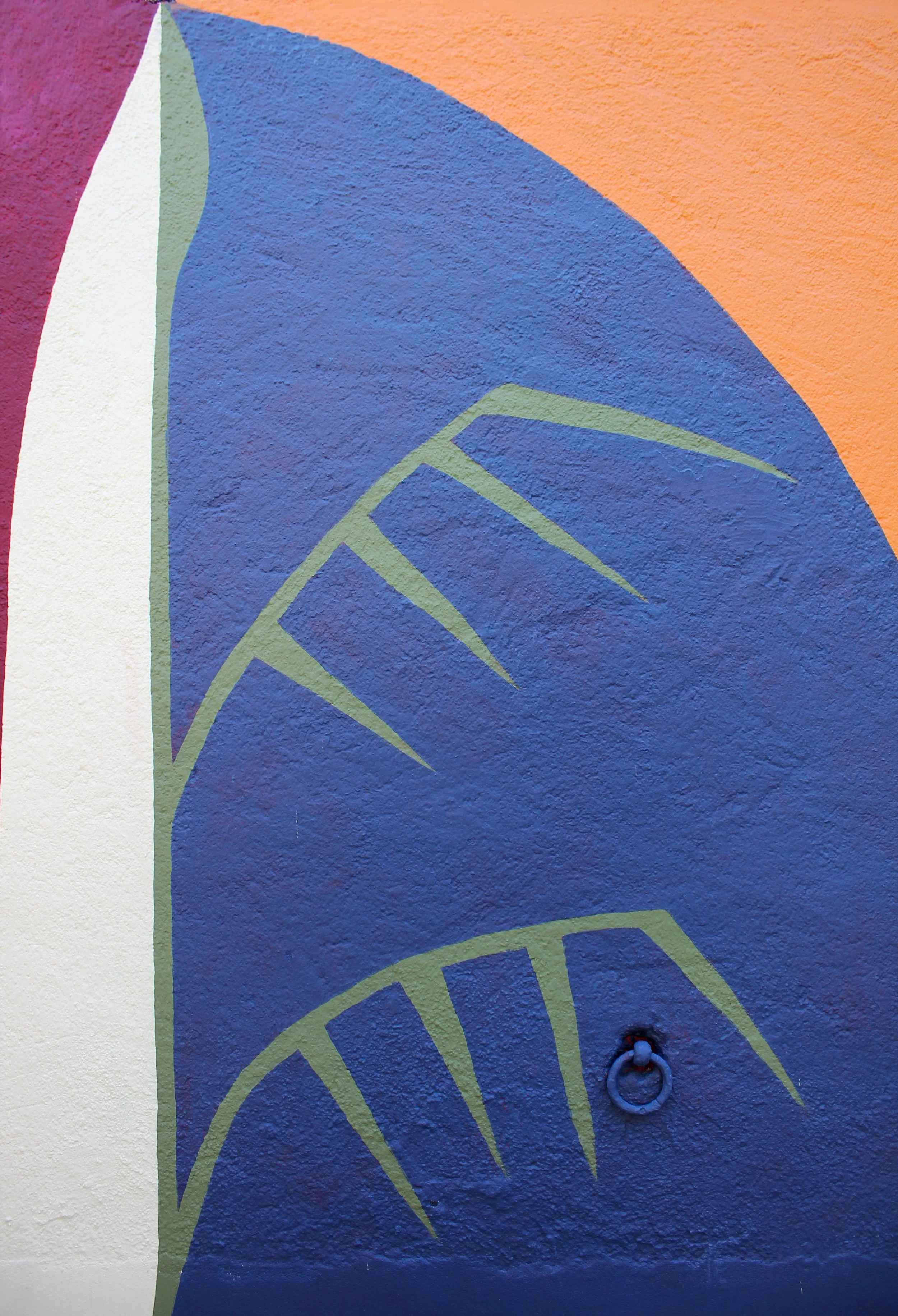 Peinture murale colorée avec des formes géométriques et un cercle métallique en bas à droite.
