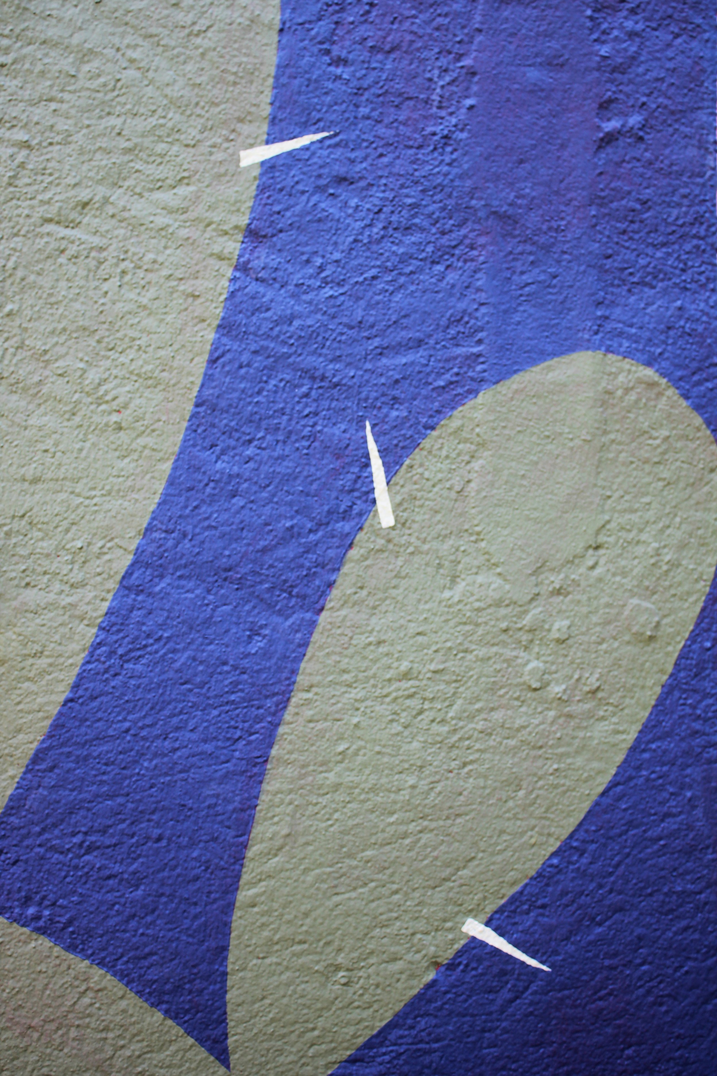 Détail d'une fresque murale avec des formes abstraites en vert et violet sur un mur en béton