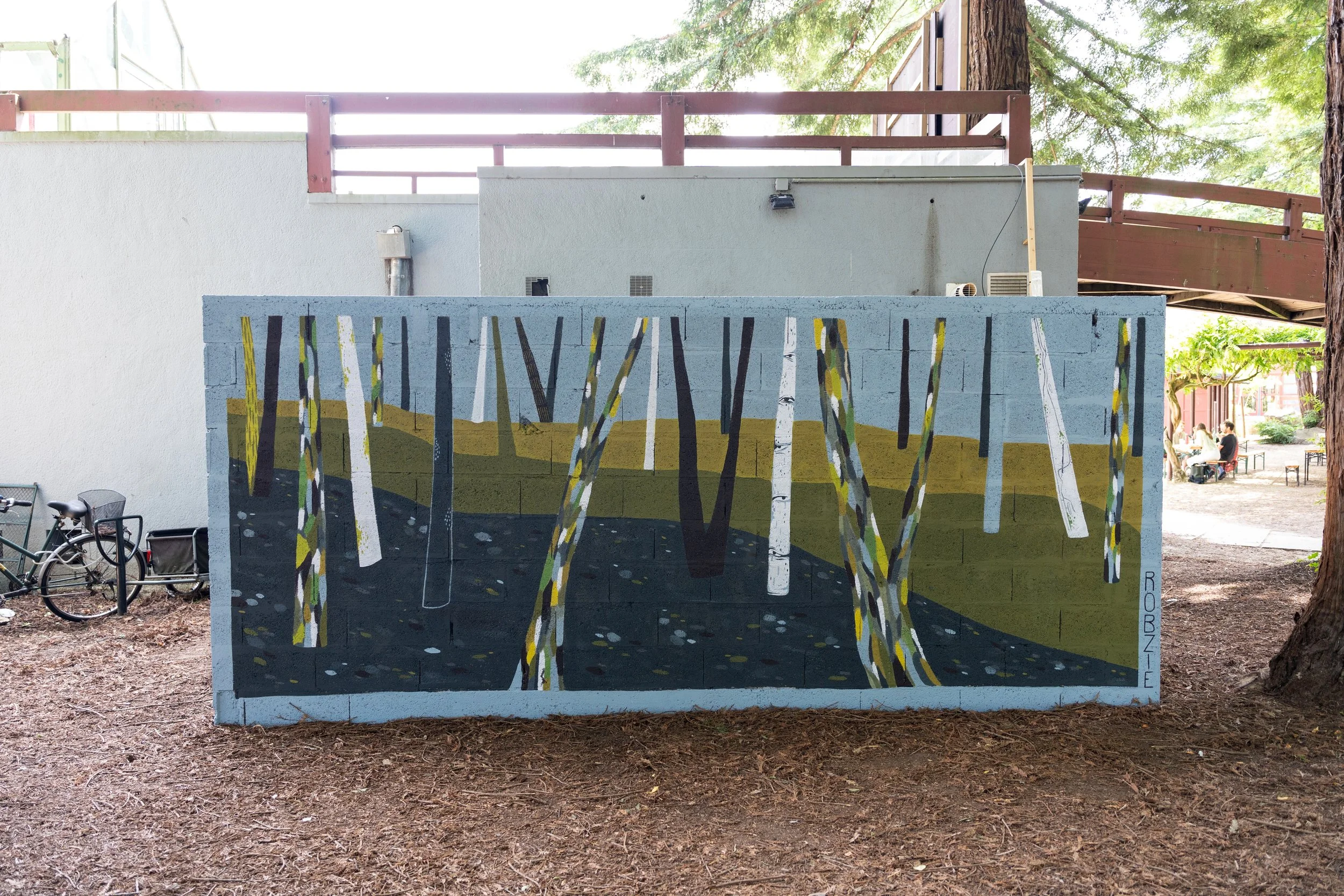 Un mur avec une peinture représentant des arbres dans une forêt.