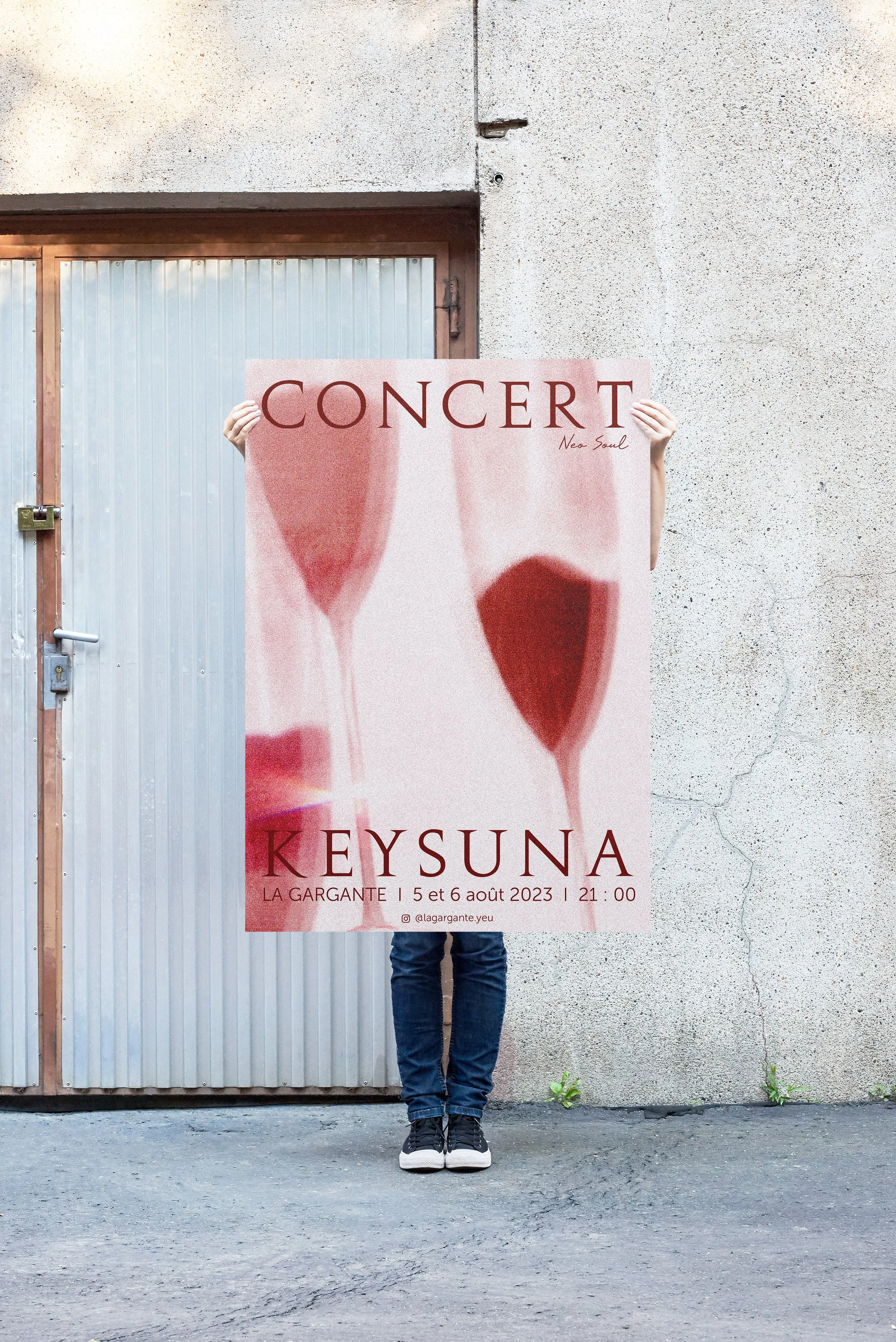 Une personne tient une affiche pour un concert devant un mur en béton.