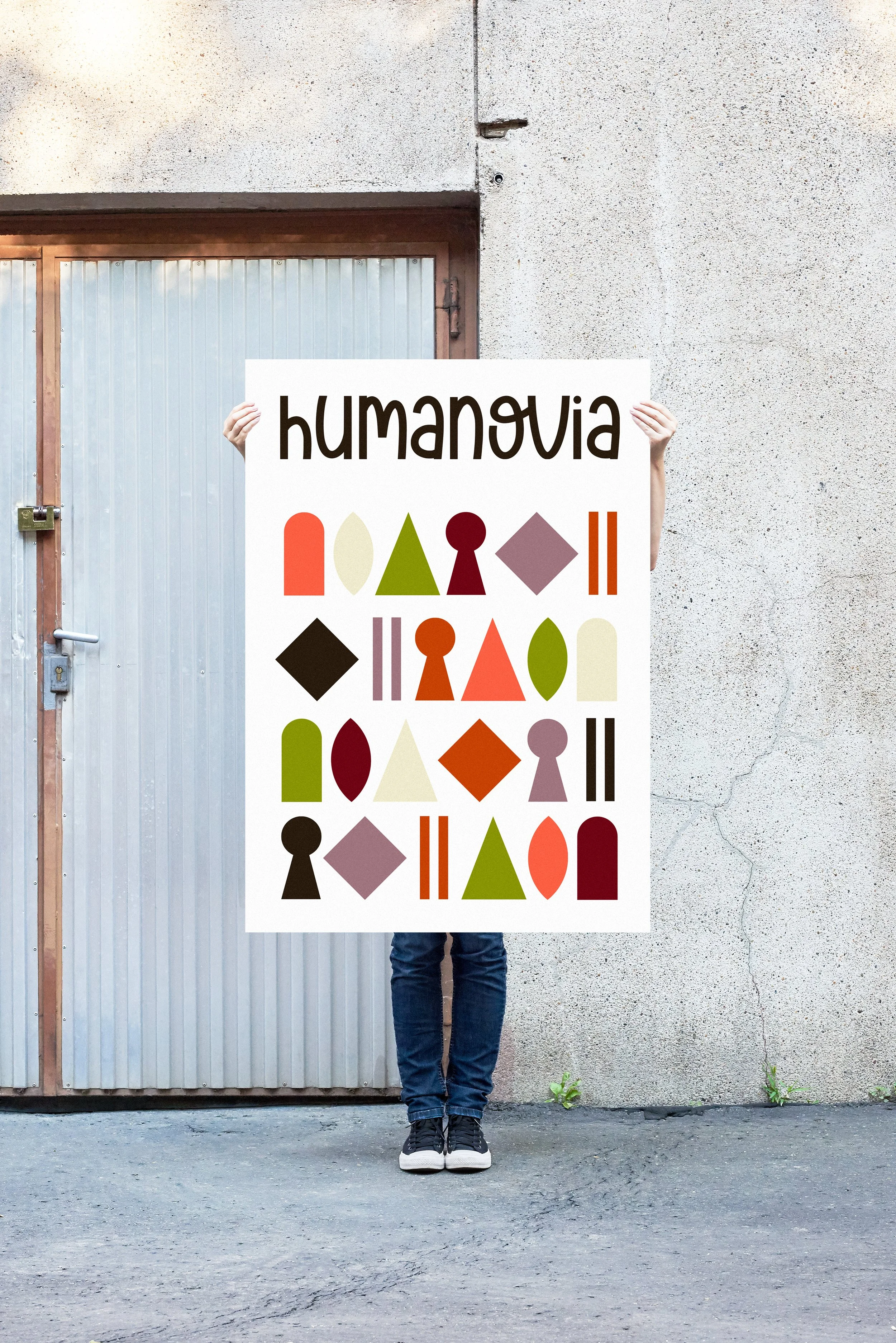 Une personne tient une pancarte avec le mot "humanova" et des formes géométriques colorées devant un mur en béton.