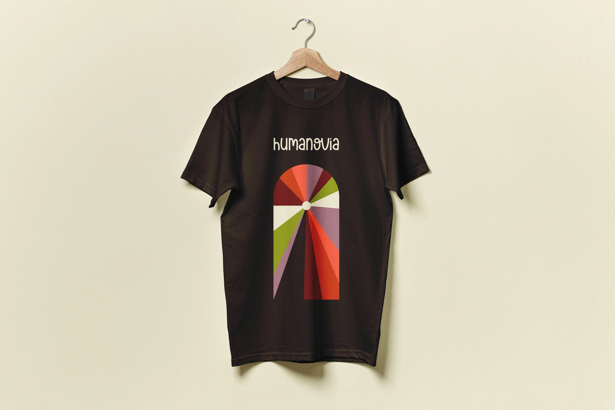 Un t-shirt noir suspendu sur un cintre en bois, avec un graphique en forme d'arc coloré et le mot 'humanova' écrit au-dessus.