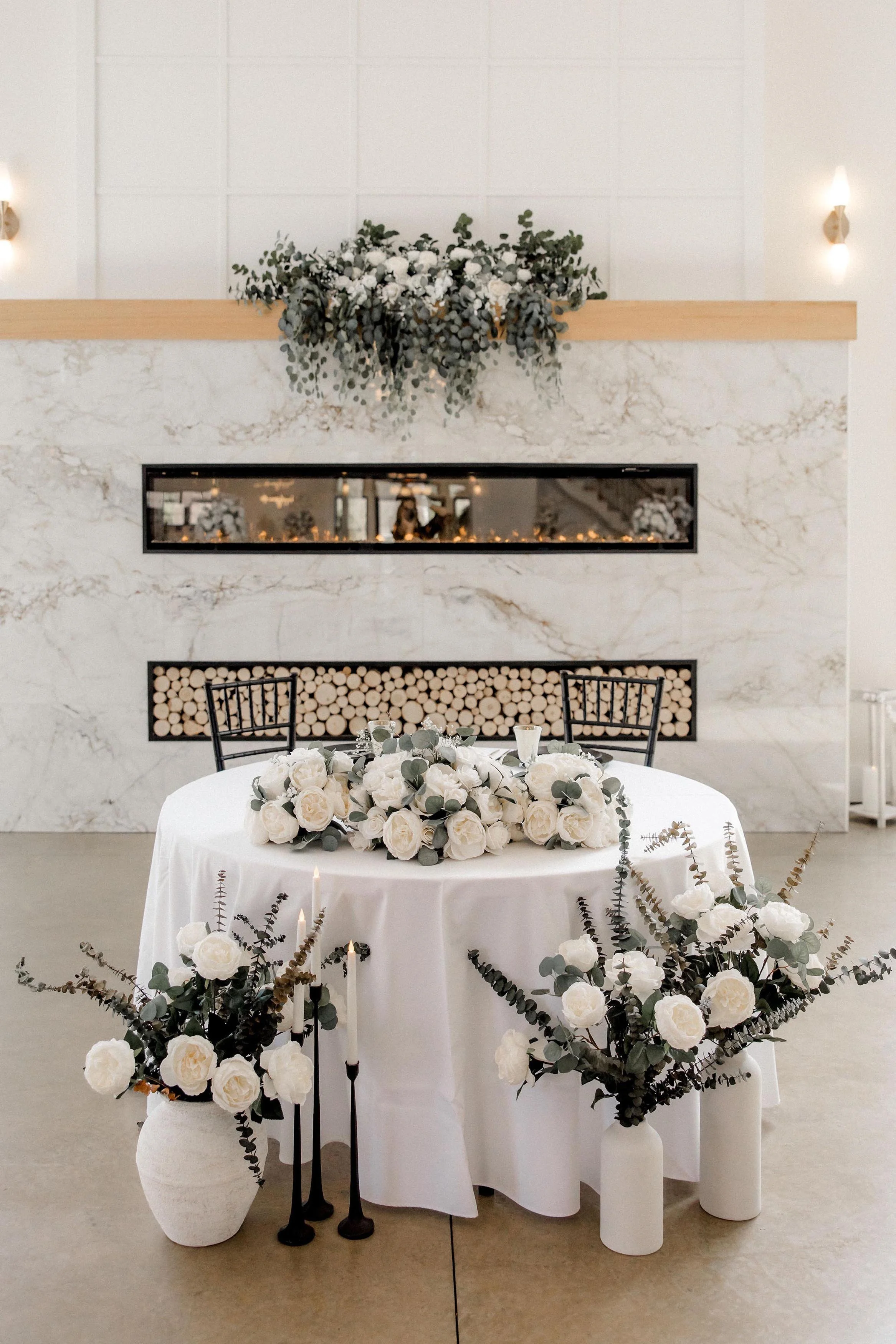 sweetheart table set up in front of the marble fireplace with white floral arragnements