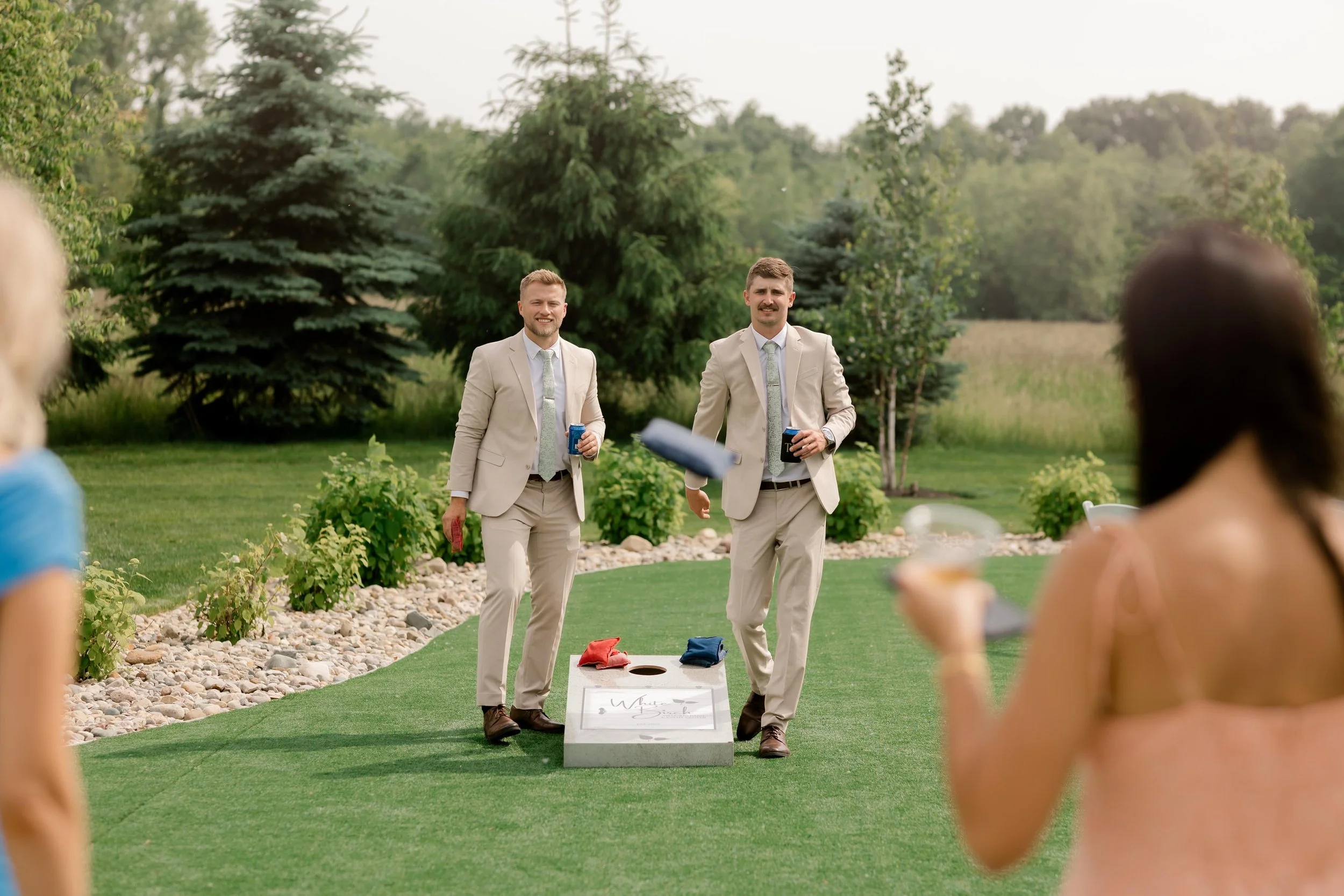 two wedding guests playing corn hole