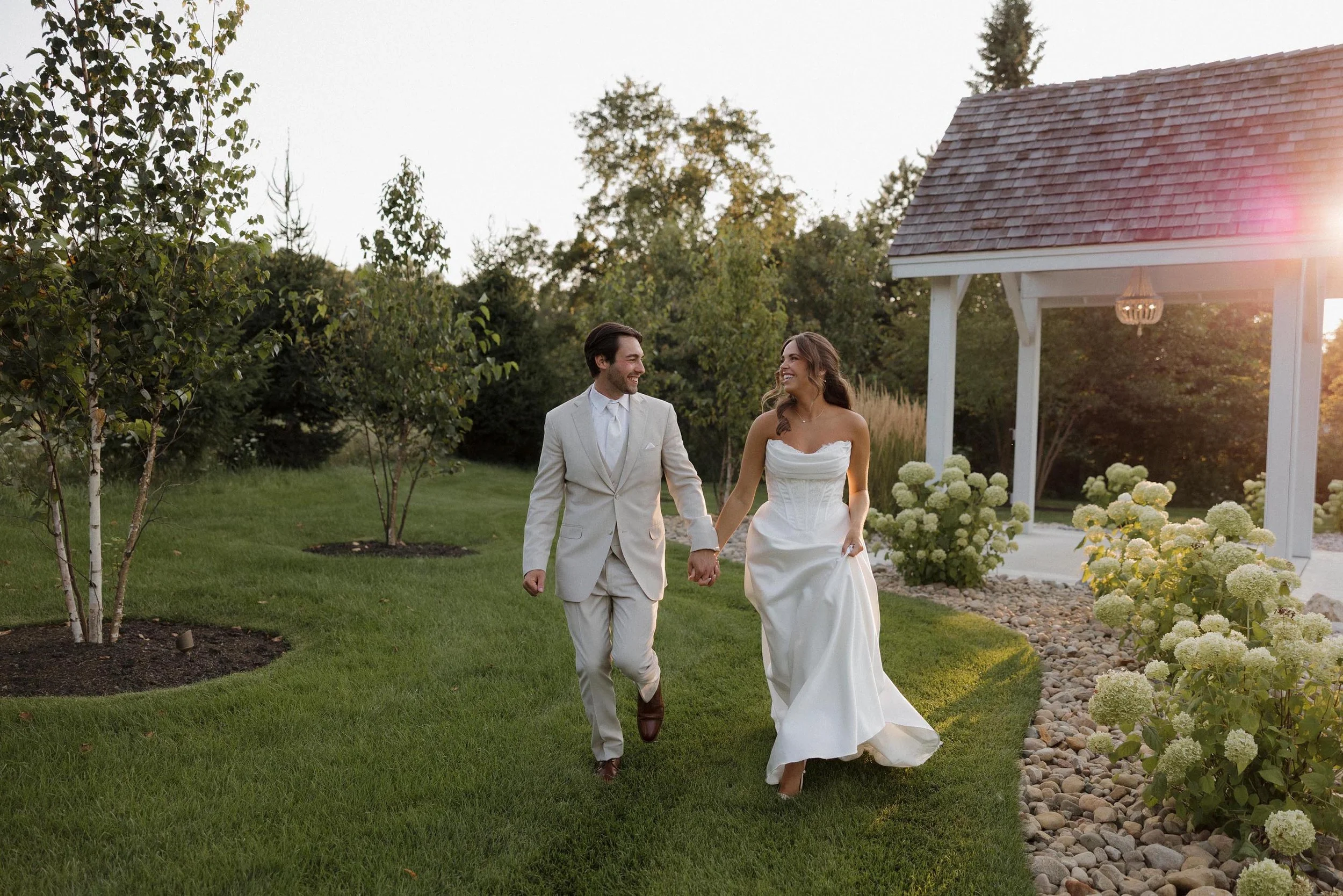 bride and groom holding hands and walking through the White Birch property