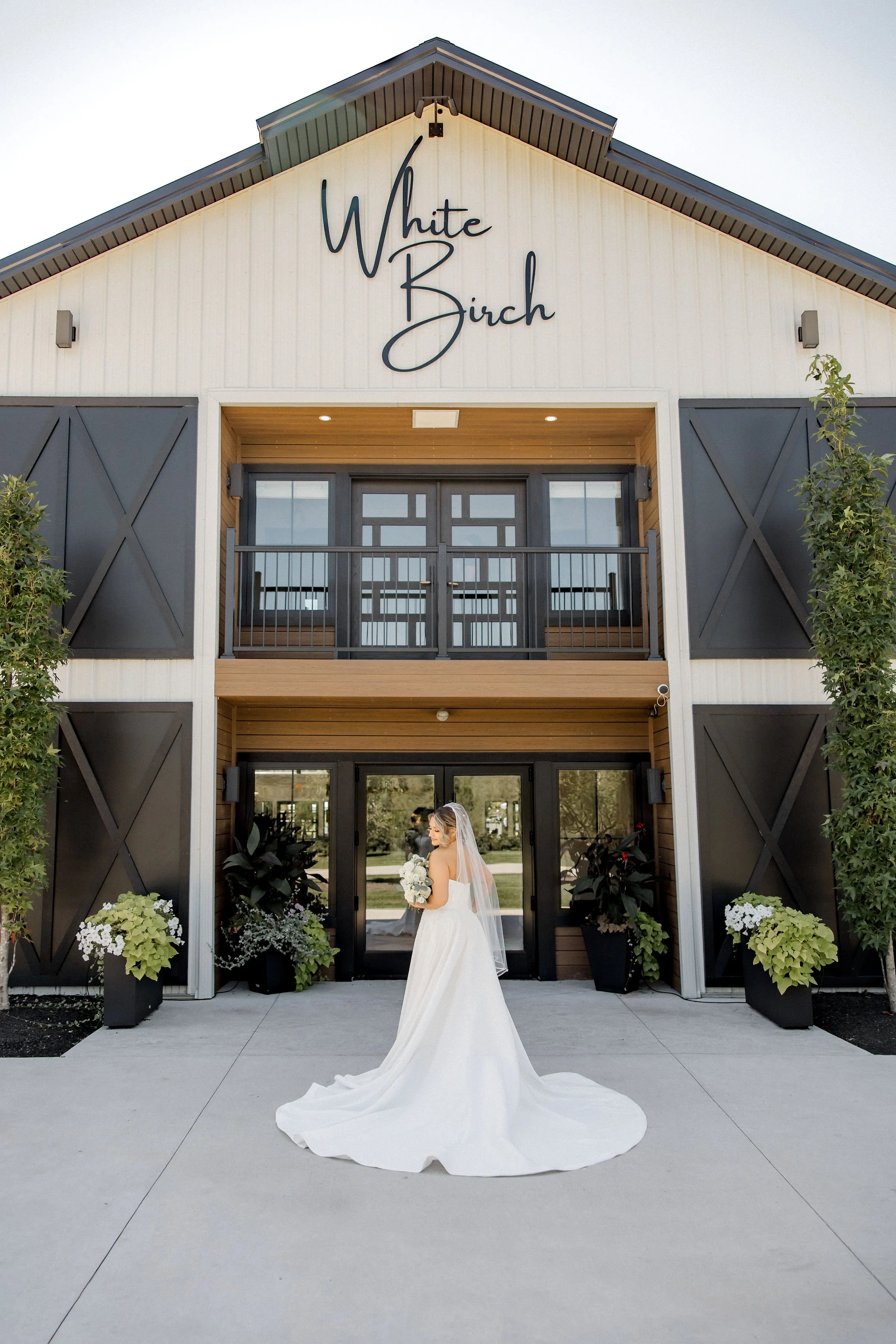 bride and groom holding hands, walking down a pathway with grassy landscaping on either side