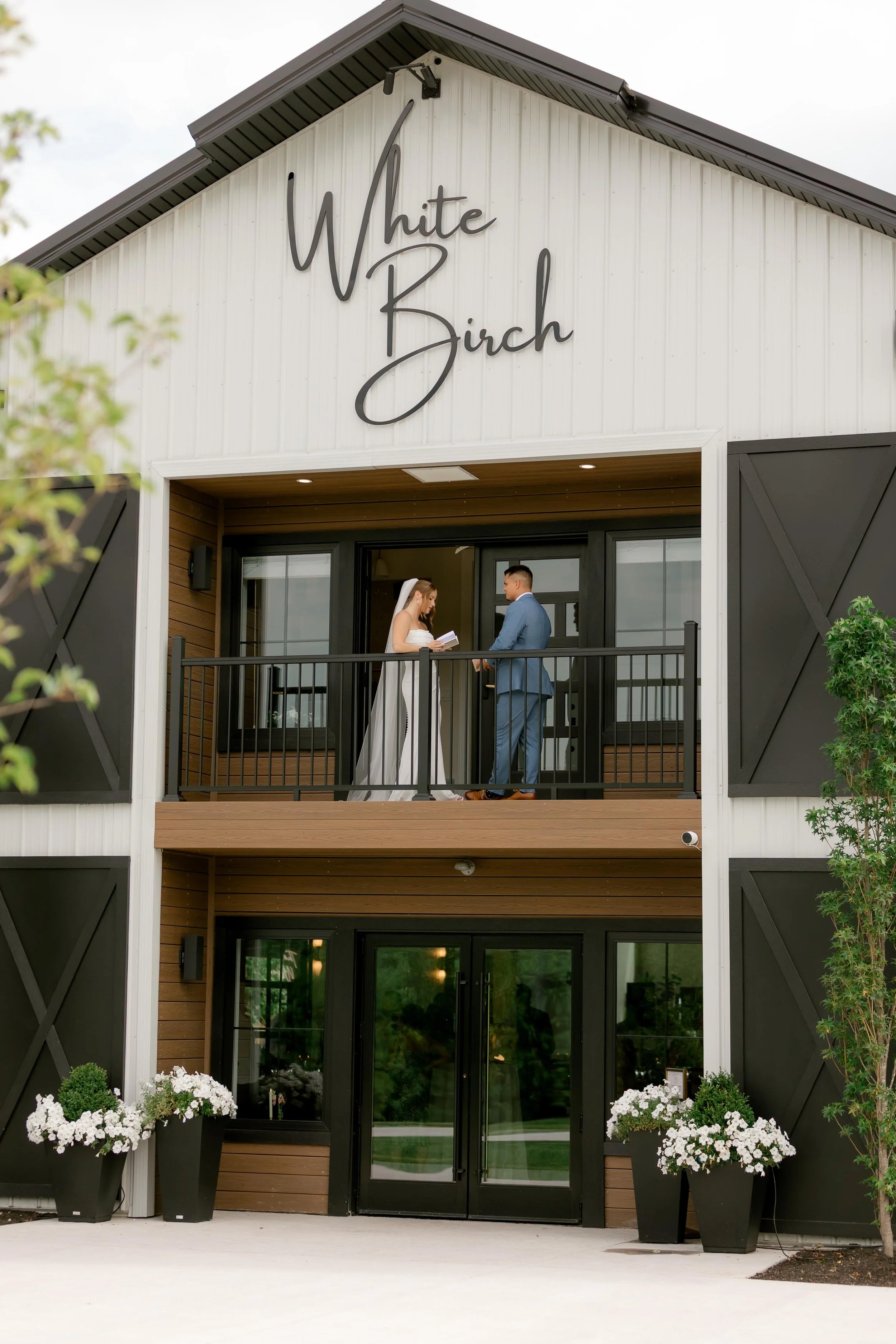 couple standing on the barn balcony on their wedding day