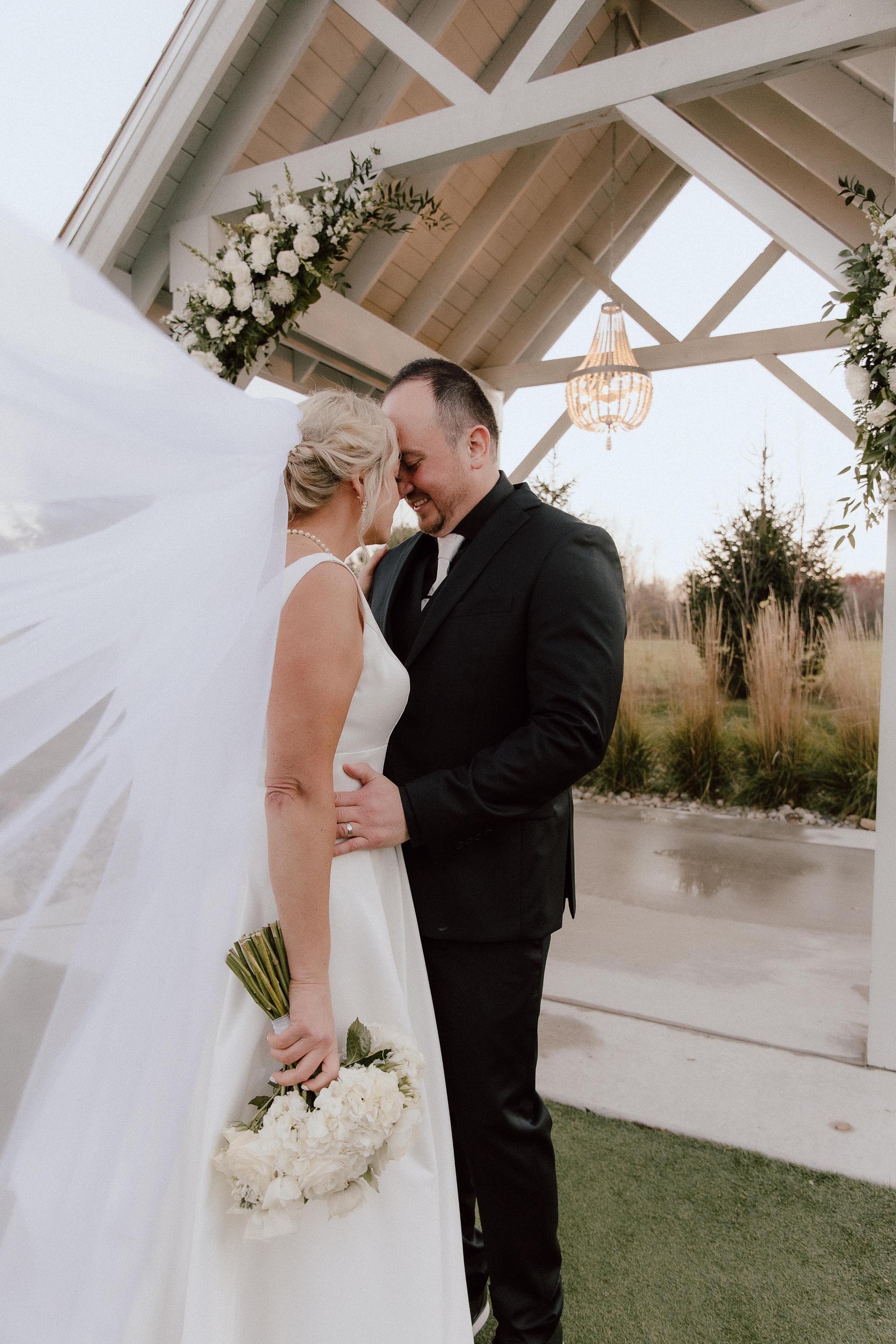 couple embracing under the open-air chapel, with the bride's veil blowing in the wind