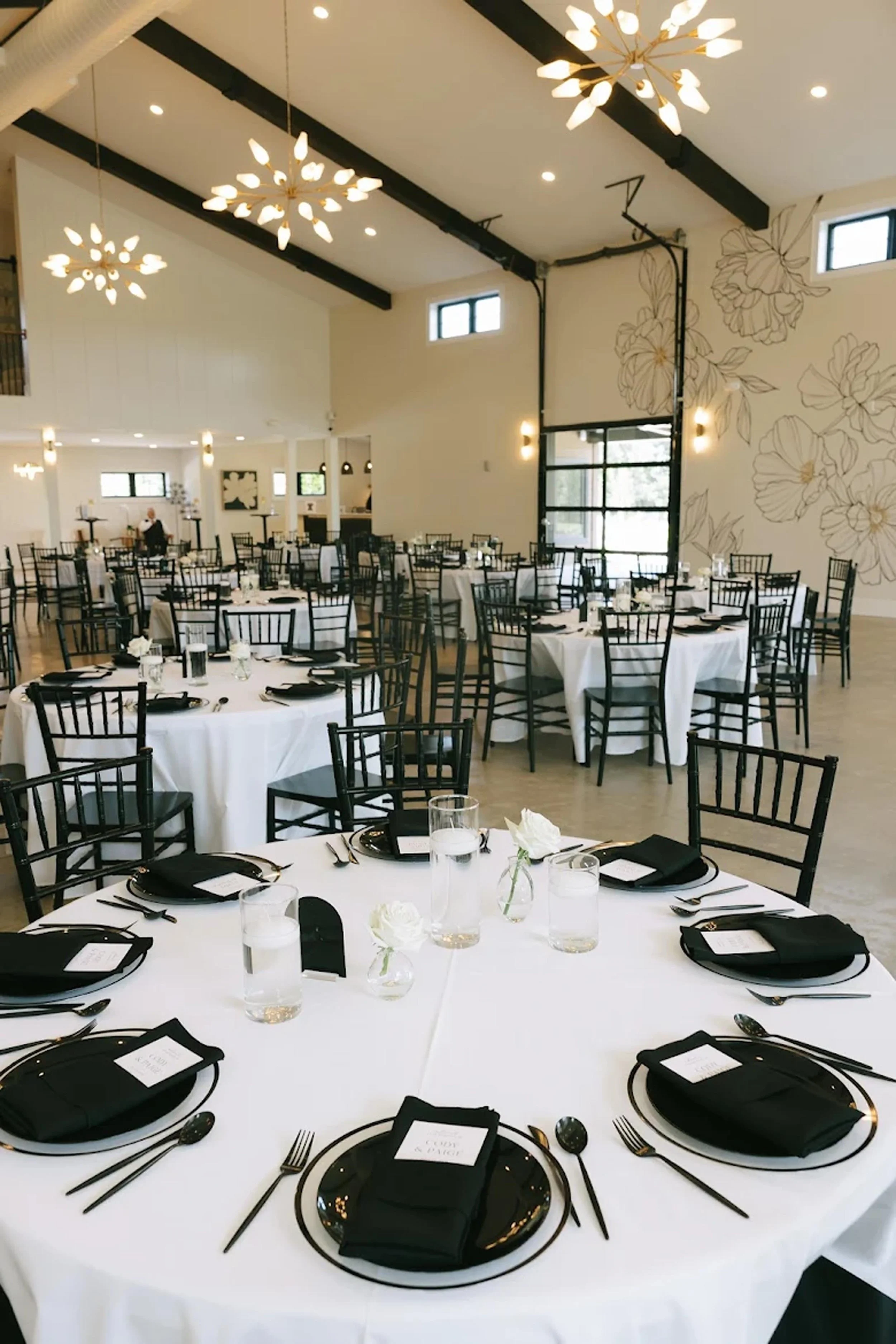 reception space set up with white tablecloths and black napkins