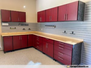 Red kitchen cabinets with a wooden countertop and a gray tiled backsplash.