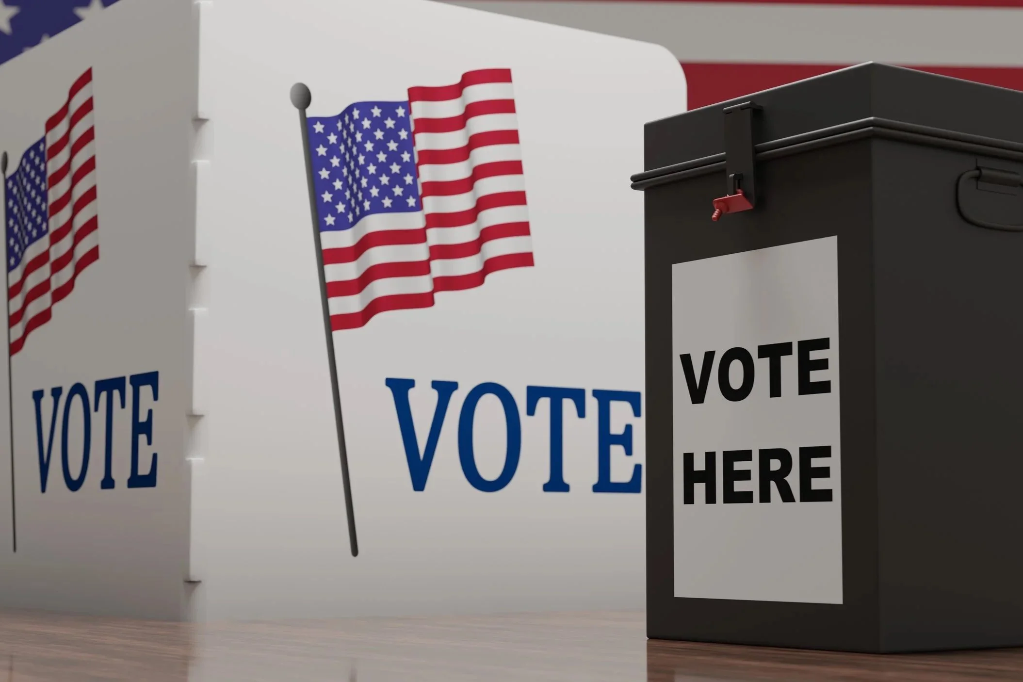 Ballot boxes with American flags and 'Vote Here' signs in a voting area.